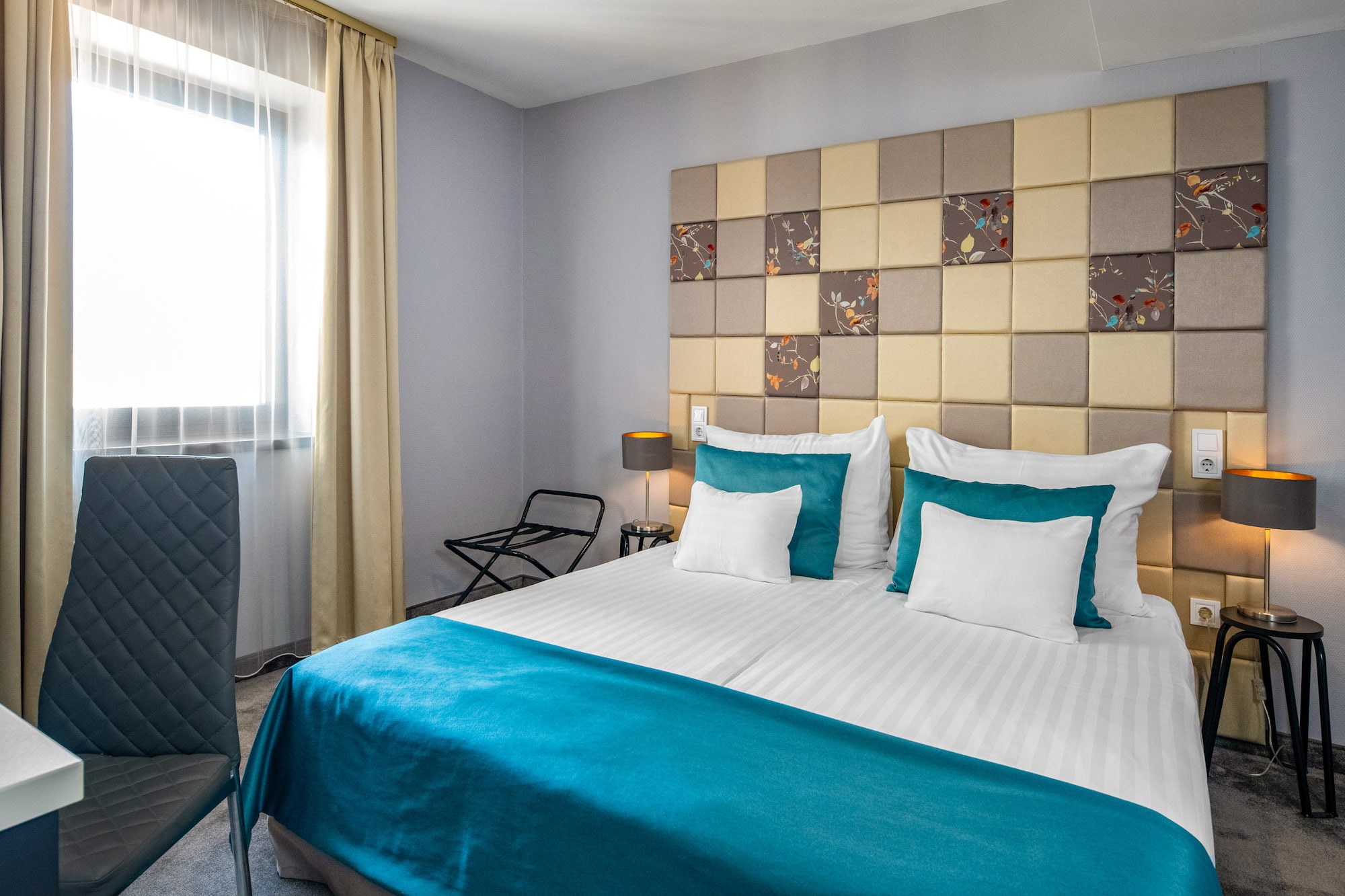 a bed with a blue blanket and a lamp in a room