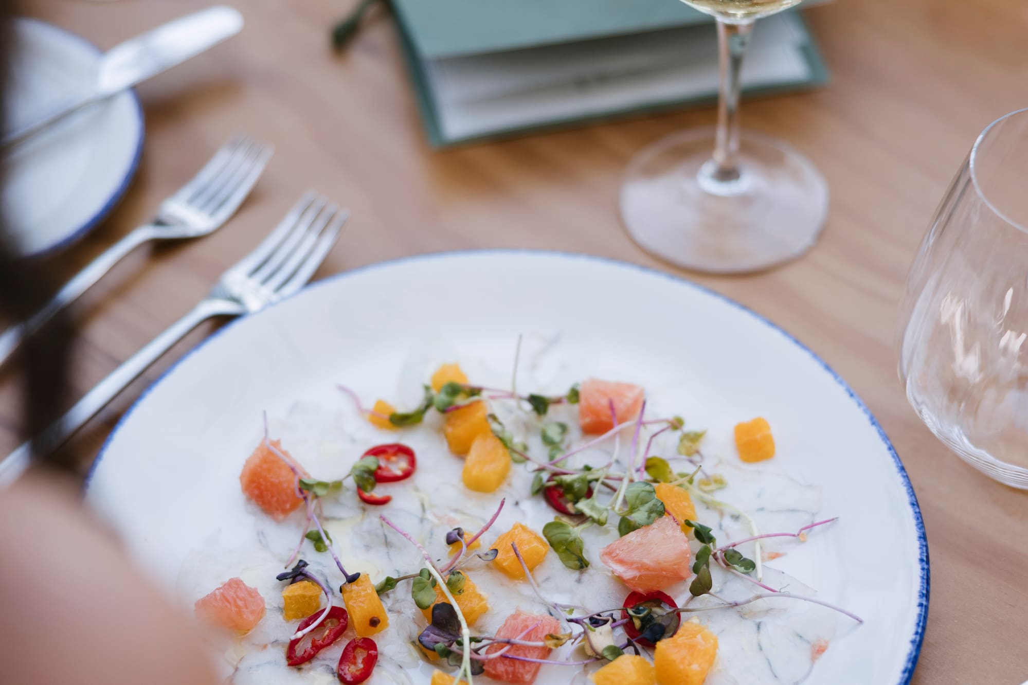 Seafood carpaccio with grapefruit, chili, microgreens, and white wine.