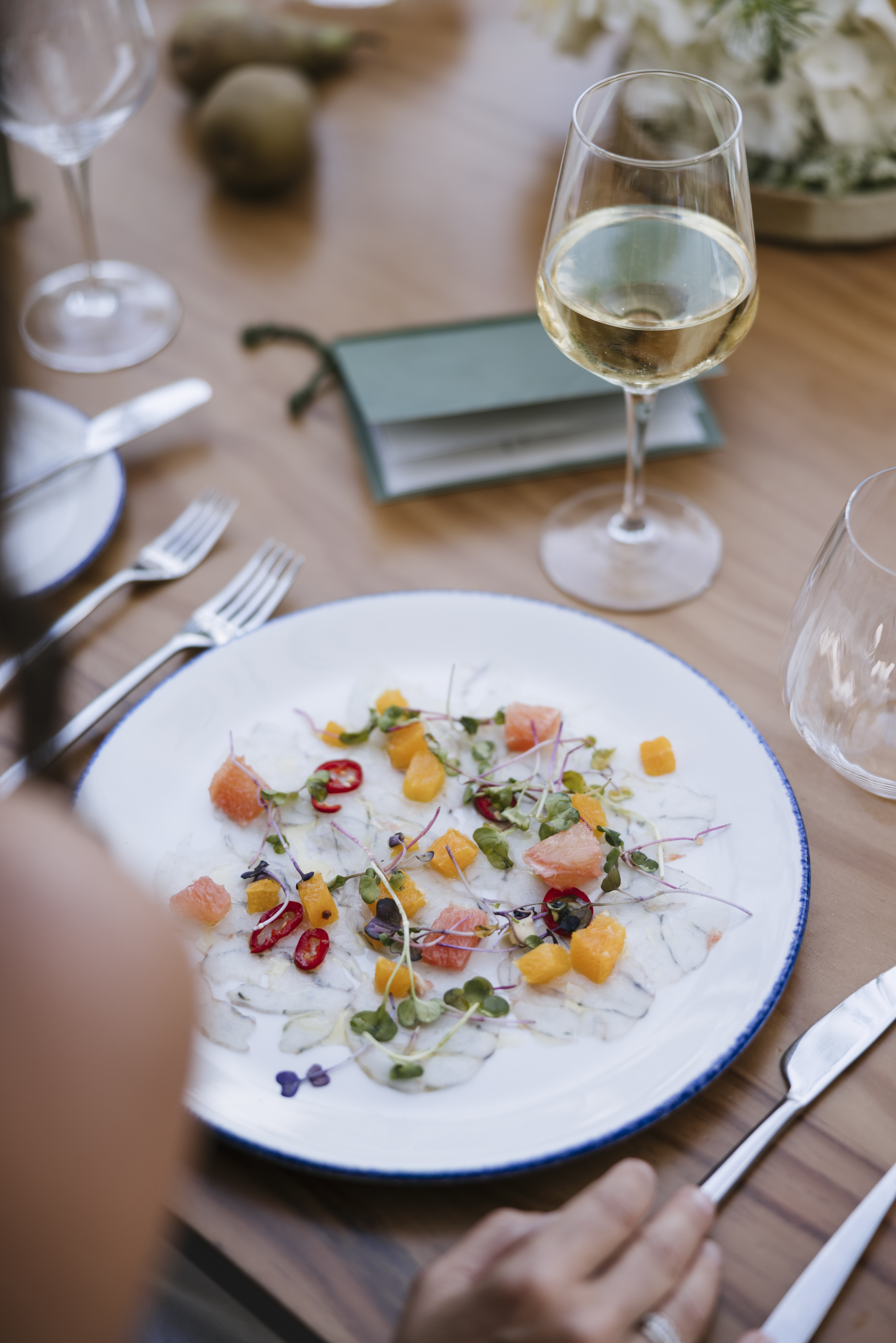 Seafood carpaccio with grapefruit, chili, microgreens, and white wine.