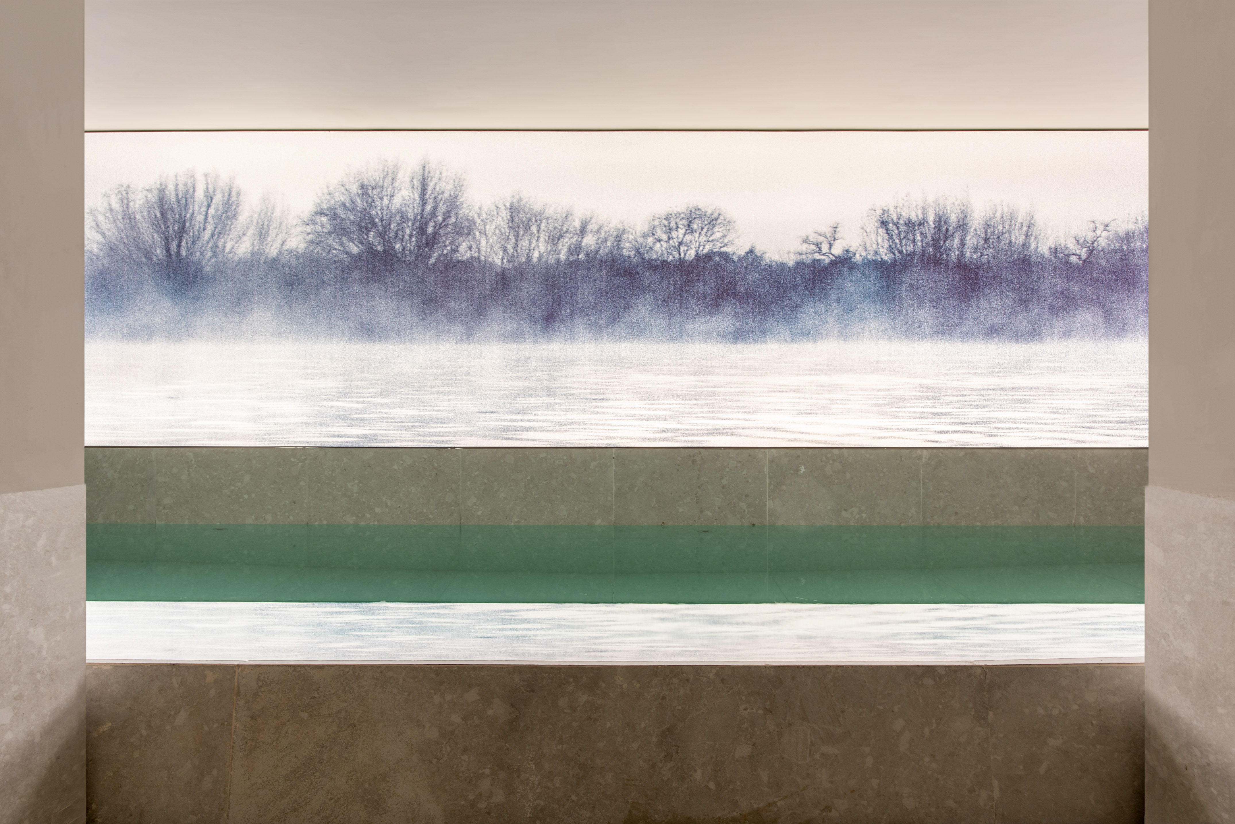 Serene indoor pool with misty winter landscape mural and green water.