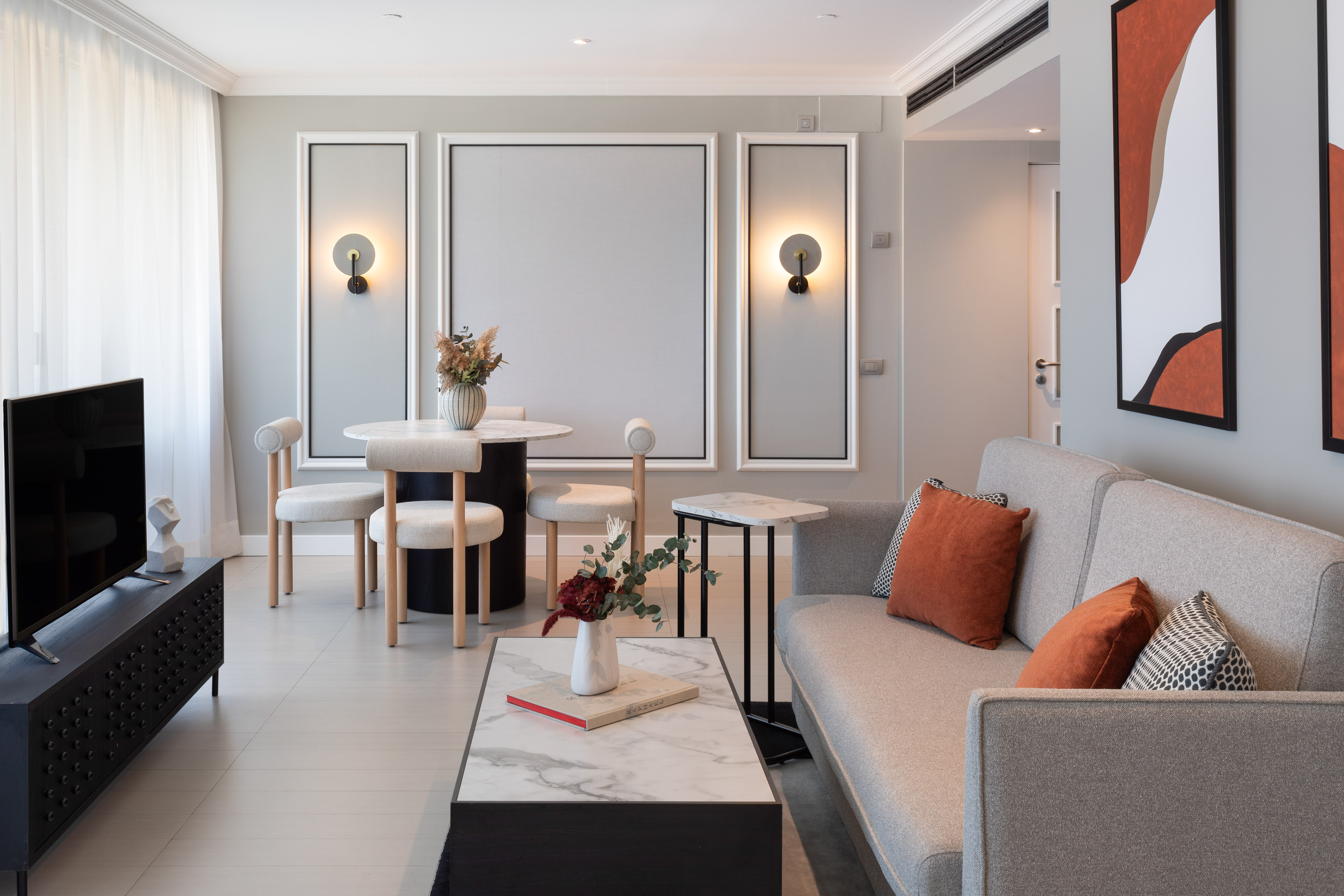 Contemporary living room with grey sofa, dining table, and modern decor.