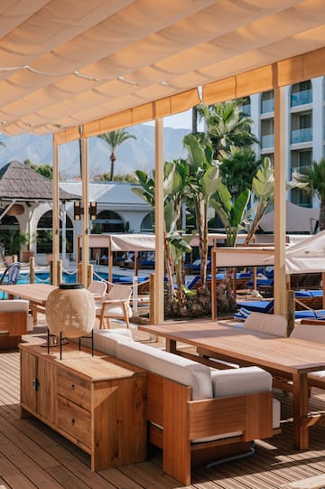 a pool with a deck with tables and chairs