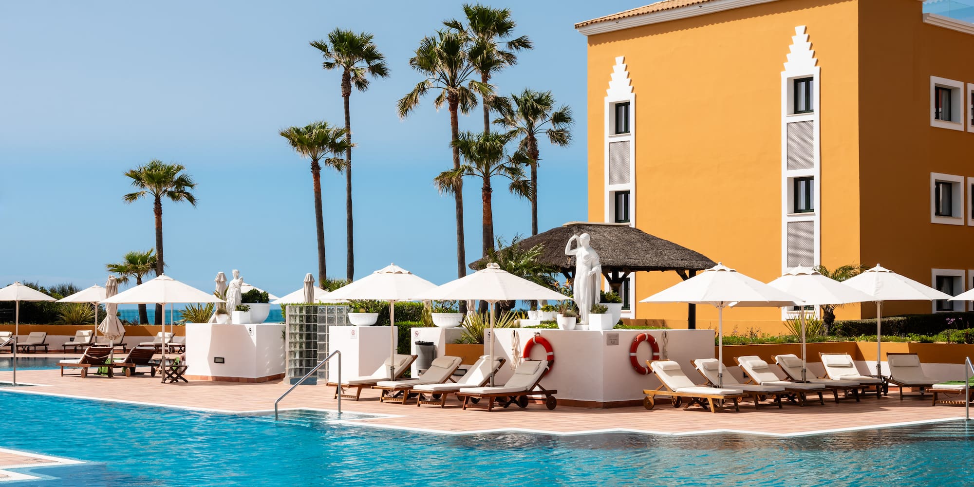 a pool with umbrellas and chairs and palm trees
