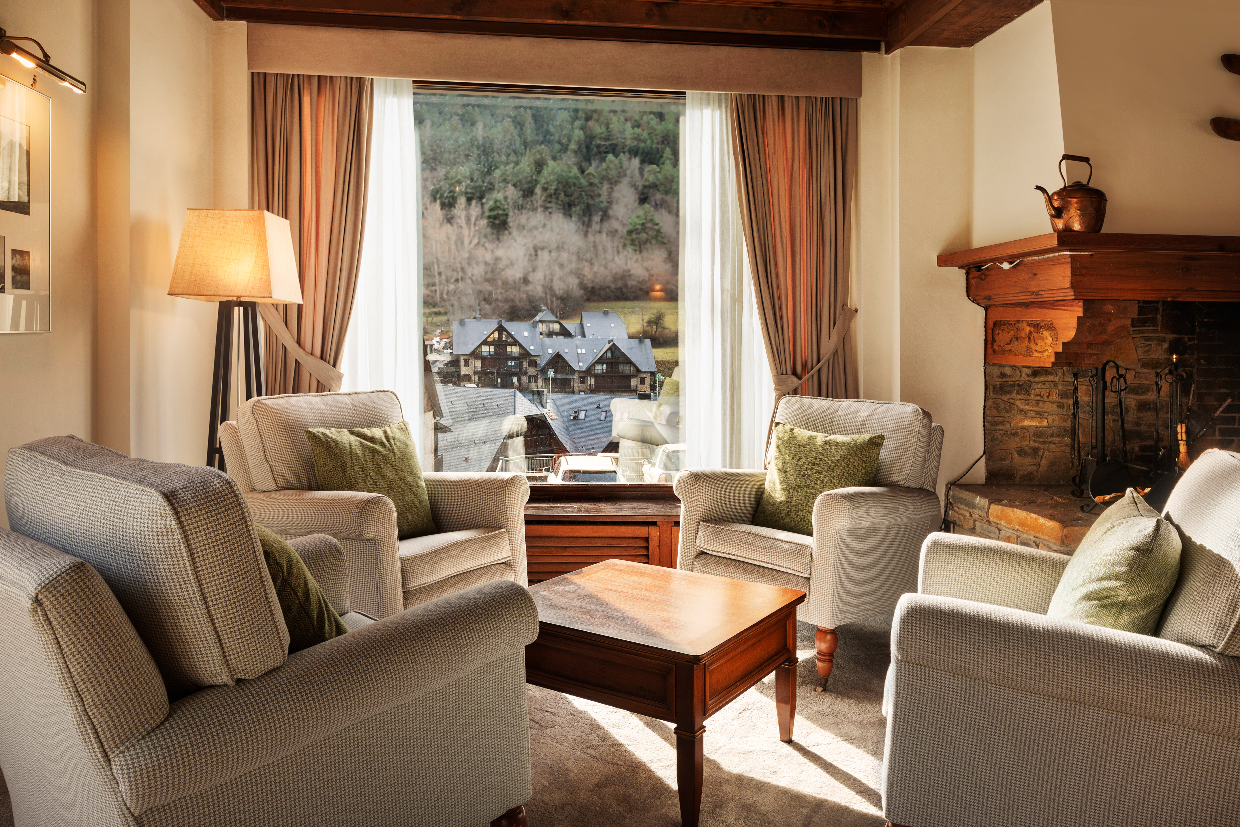 Cozy living room with fireplace, armchairs, and mountain village window view.
