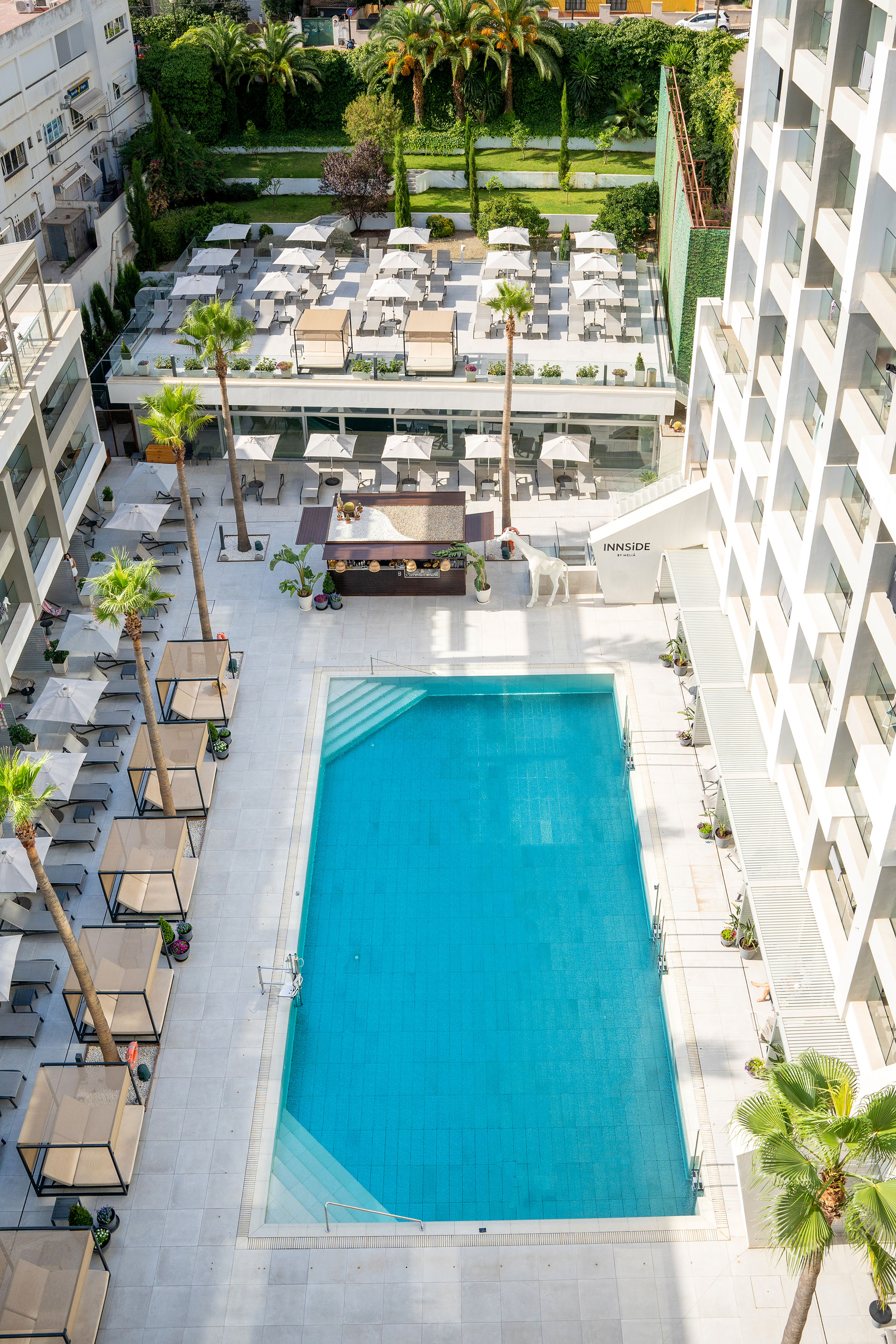 Innside by Meliá hotel pool, outdoor bar, sunbeds, and palm trees from above.