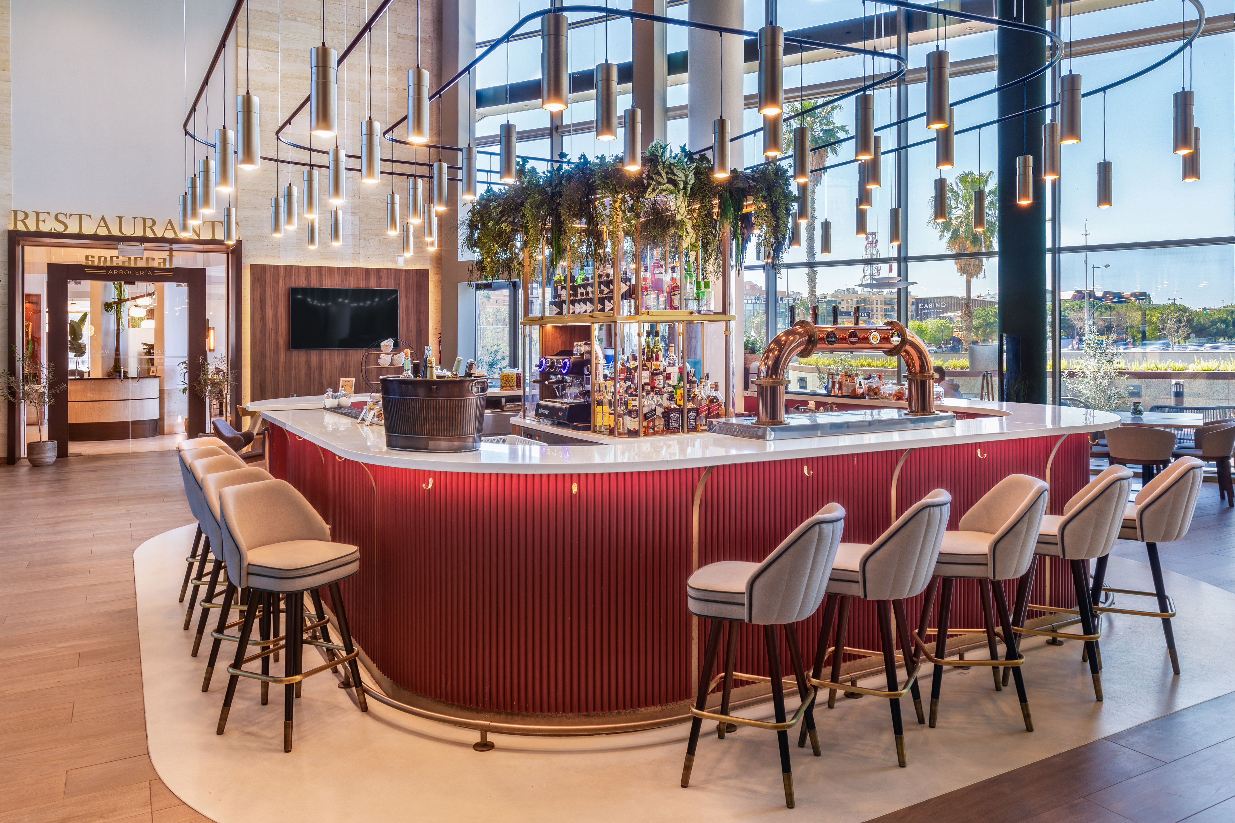 Modern red bar with bar stools, pendant lights, and a casino view.