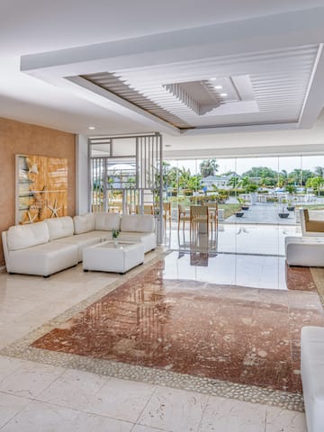 a room with white furniture and a pool in the background