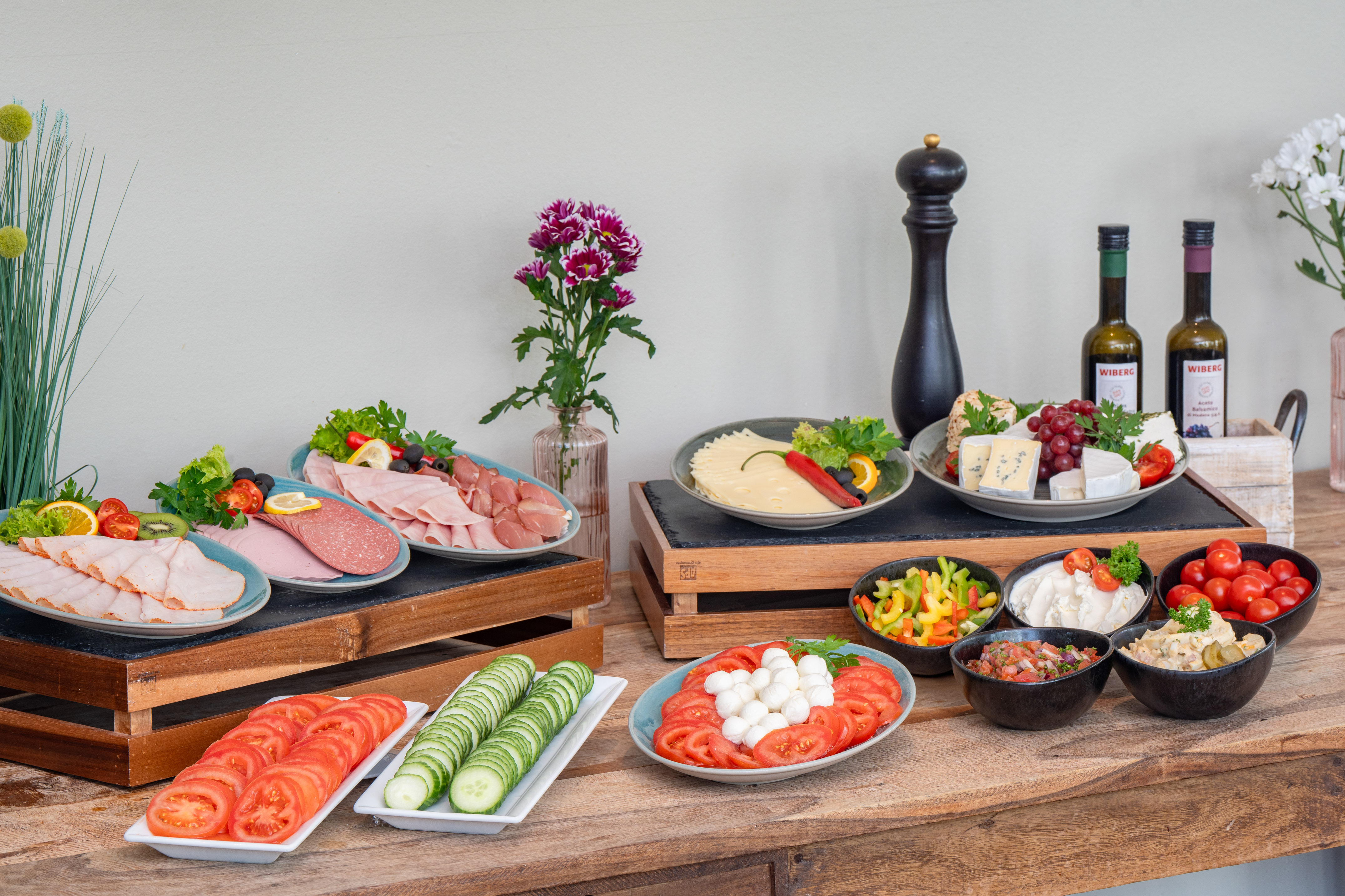 Buffet table with deli meats, cheese, fresh vegetables, and salads.