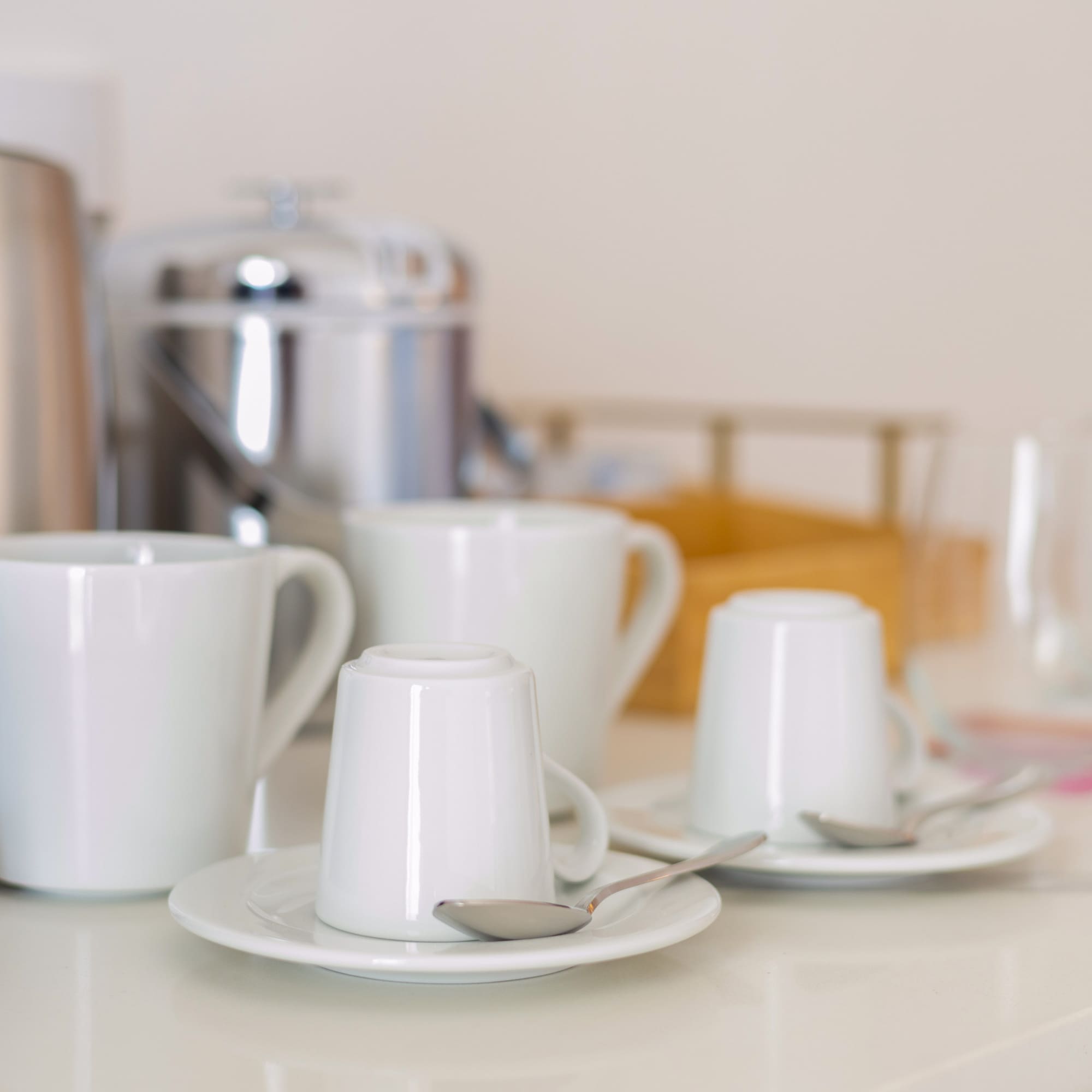a group of white cups and saucers on a white counter