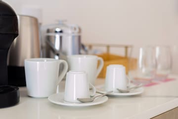 a group of white cups and saucers on a white counter