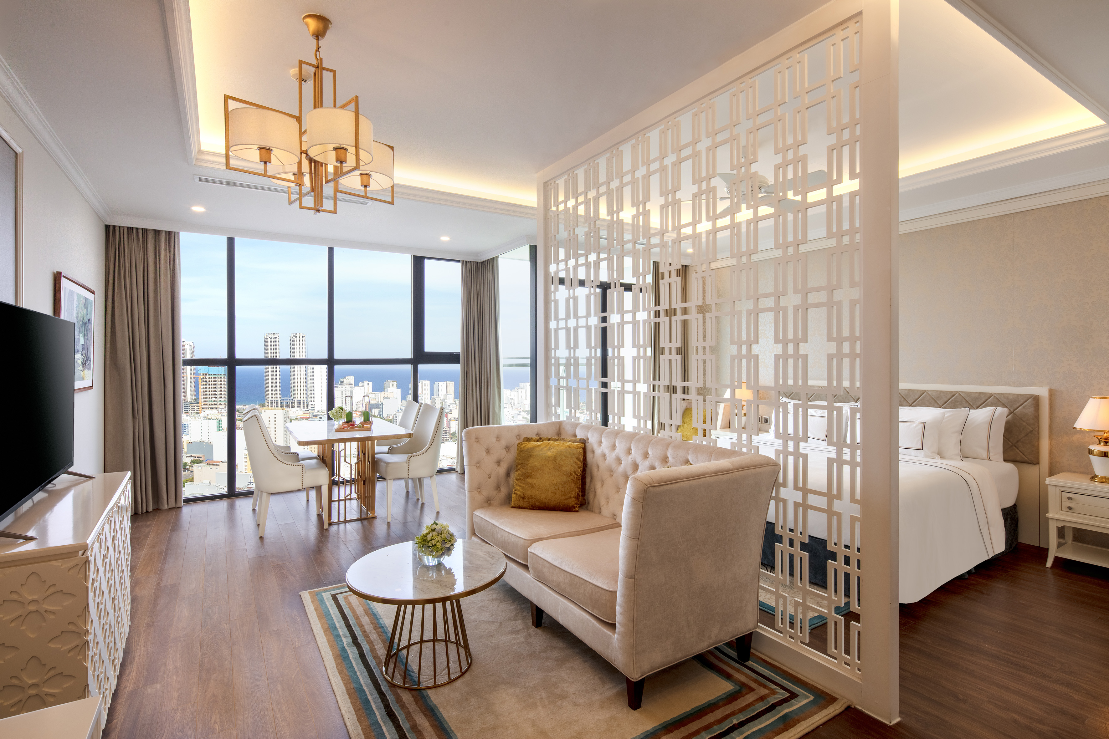 Luxurious hotel suite: living room, partitioned bedroom, and city ocean view.