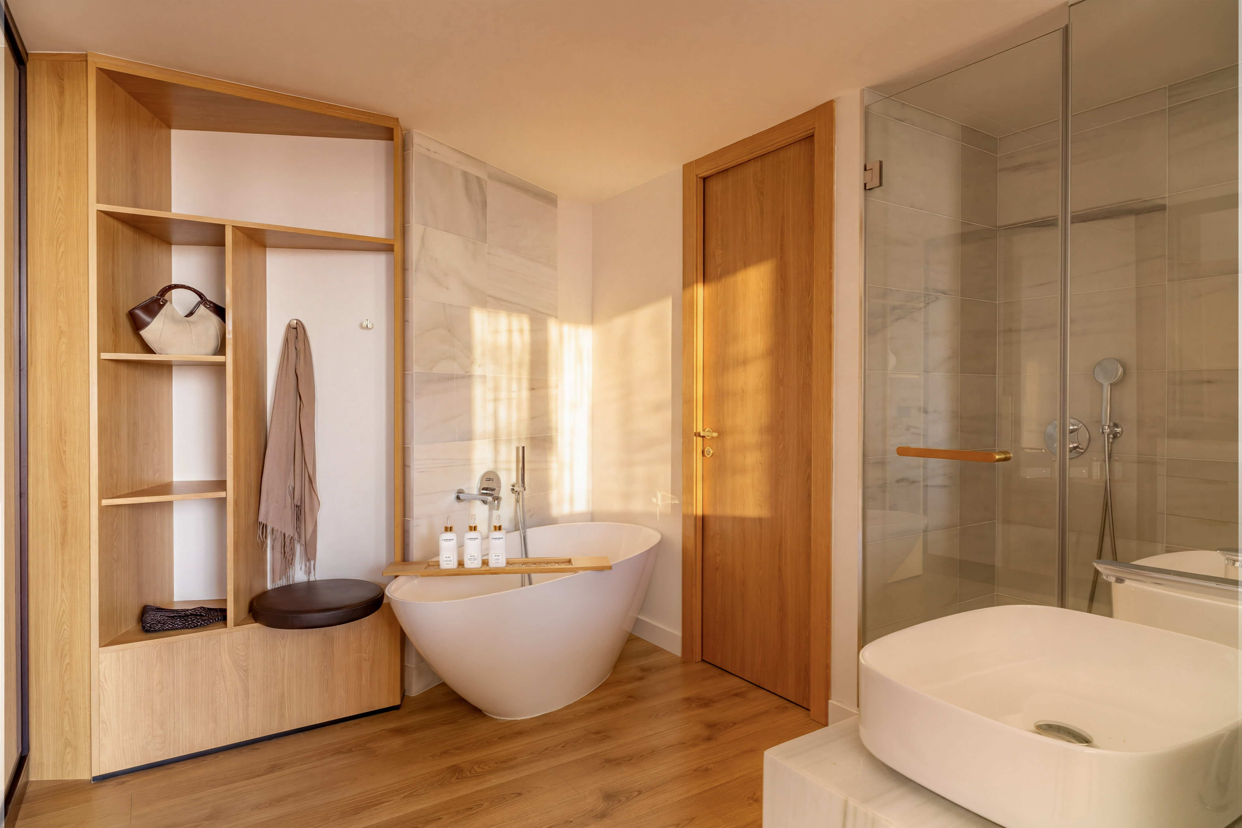 Modern bathroom with freestanding tub, wooden storage, glass shower, and white sink.