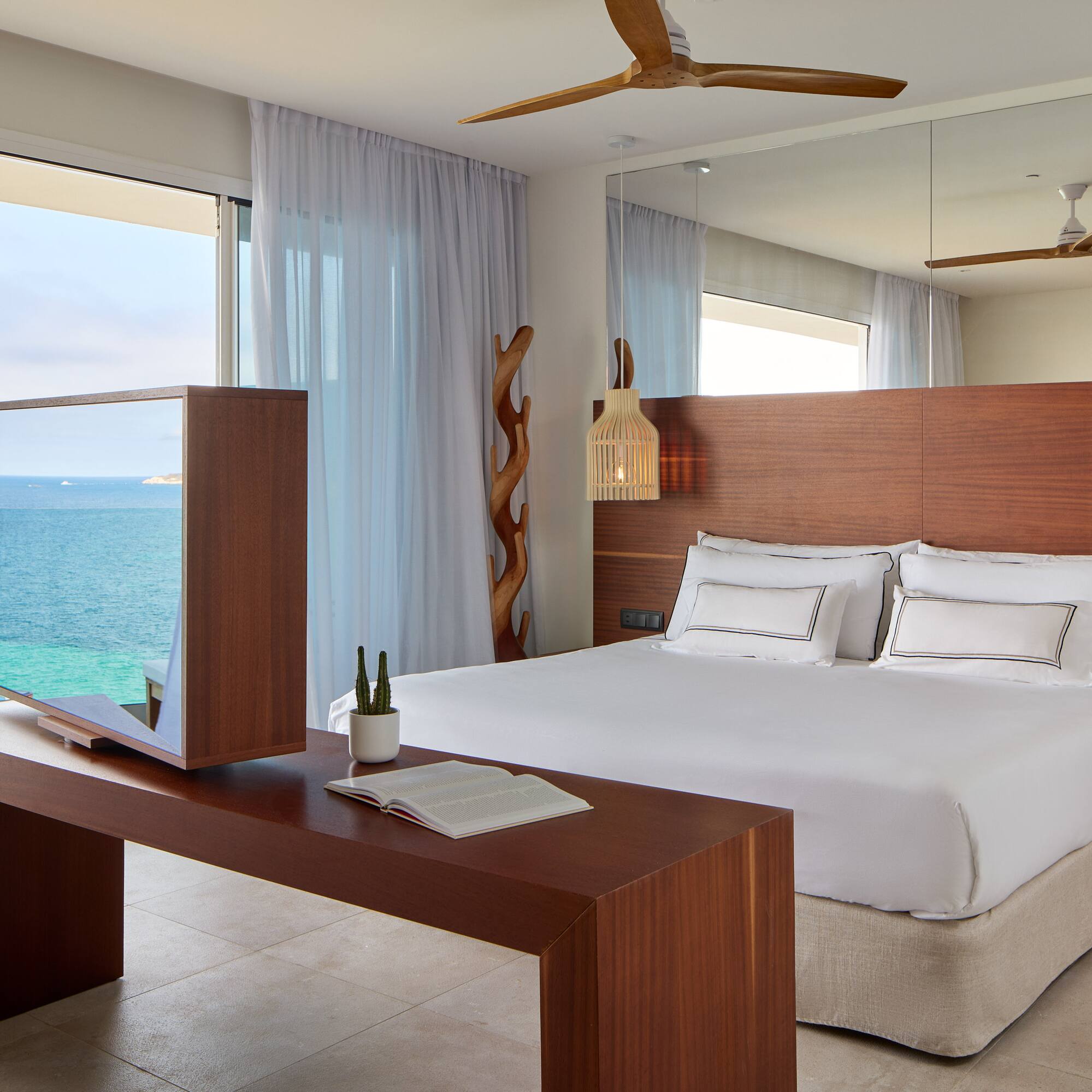 a room with a large bed and a table with a mirror and ocean view