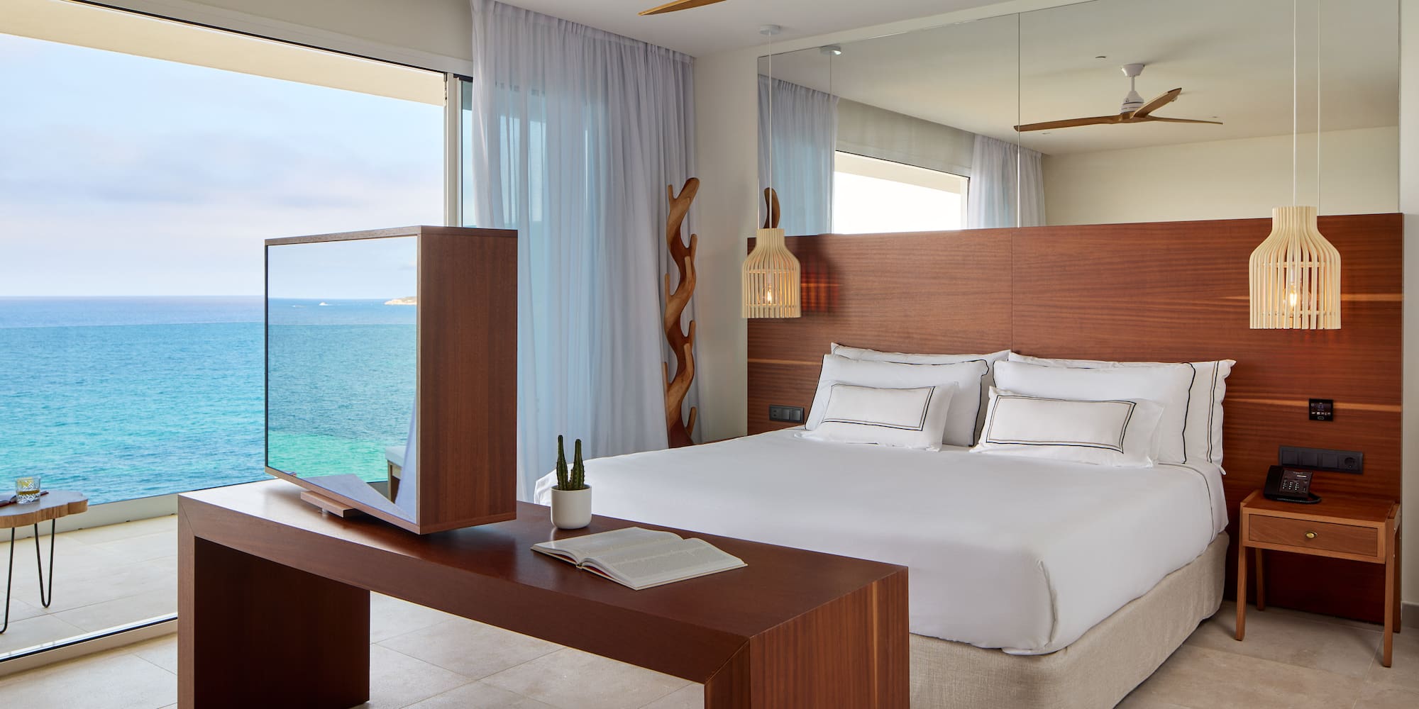 a room with a large bed and a table with a mirror and ocean view