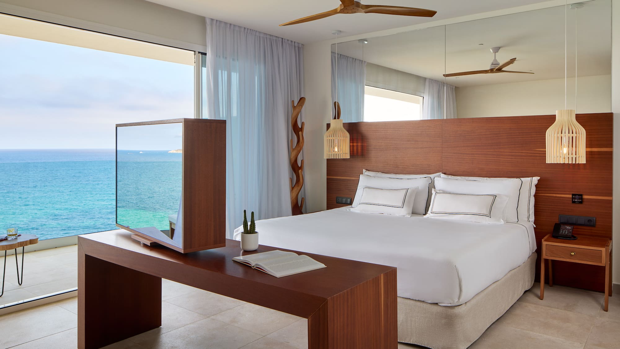 a room with a large bed and a table with a mirror and ocean view