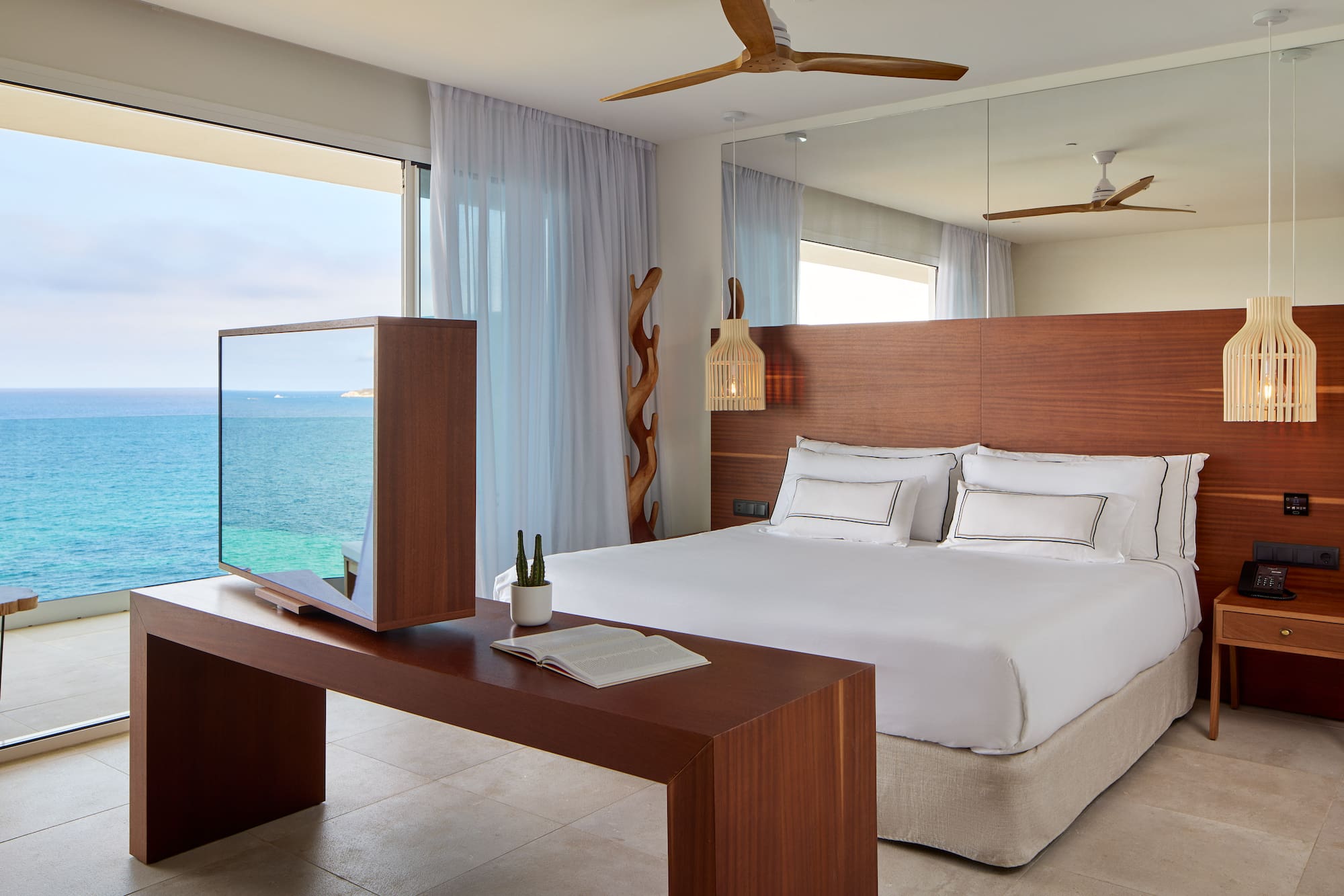 a room with a large bed and a table with a mirror and ocean view