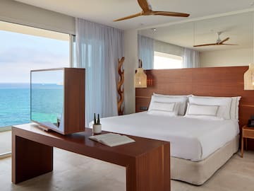 a room with a large bed and a table with a mirror and ocean view