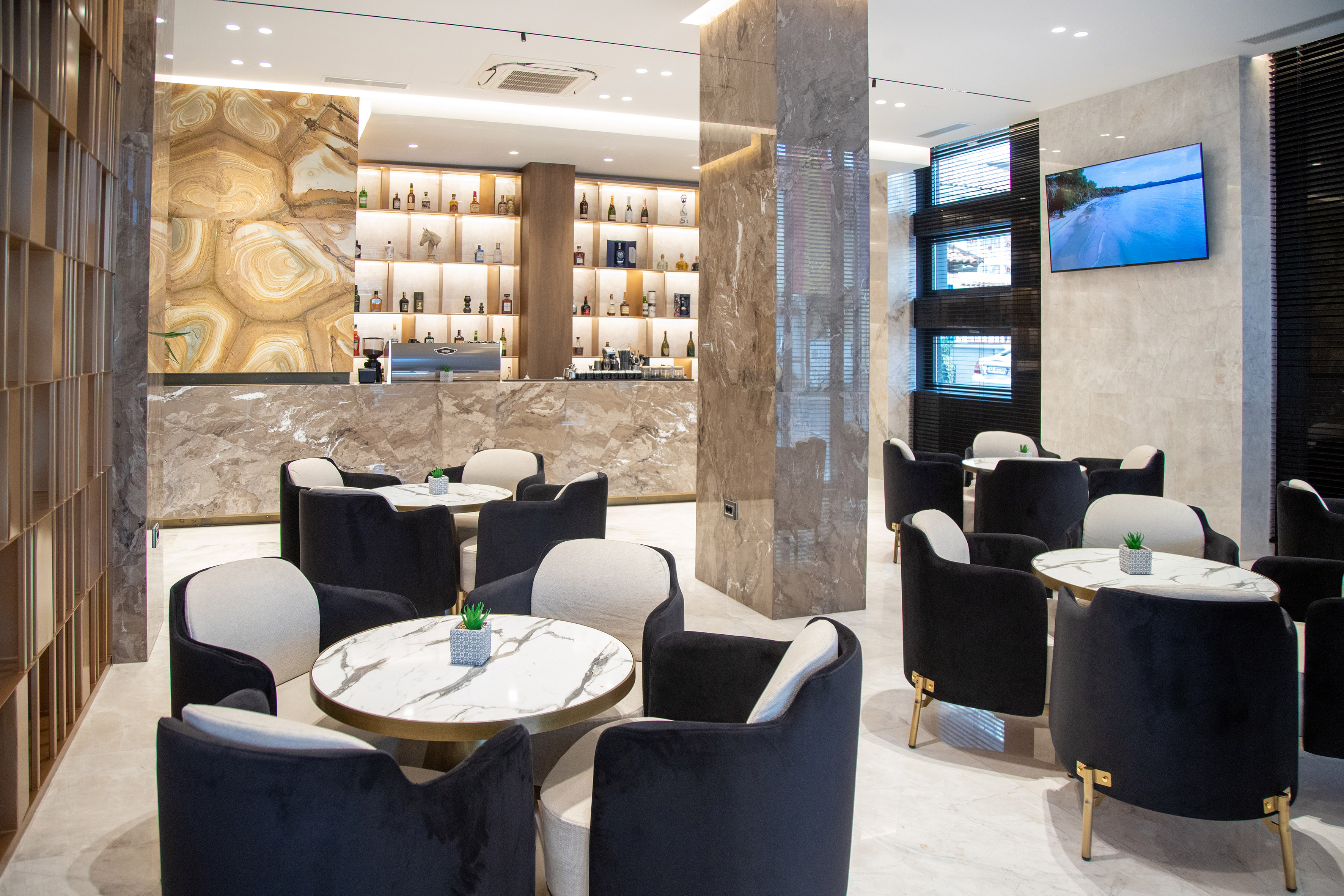 Modern hotel lounge cafe bar with marble counters and velvet seating.
