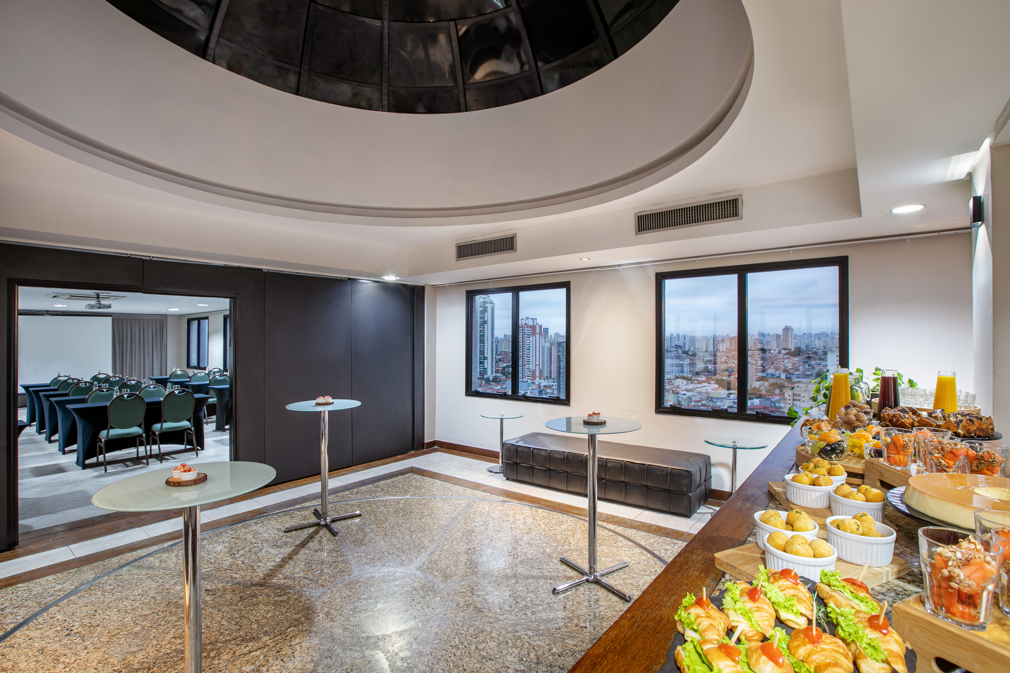 Hotel event space with catering buffet, city view, and meeting room entrance.