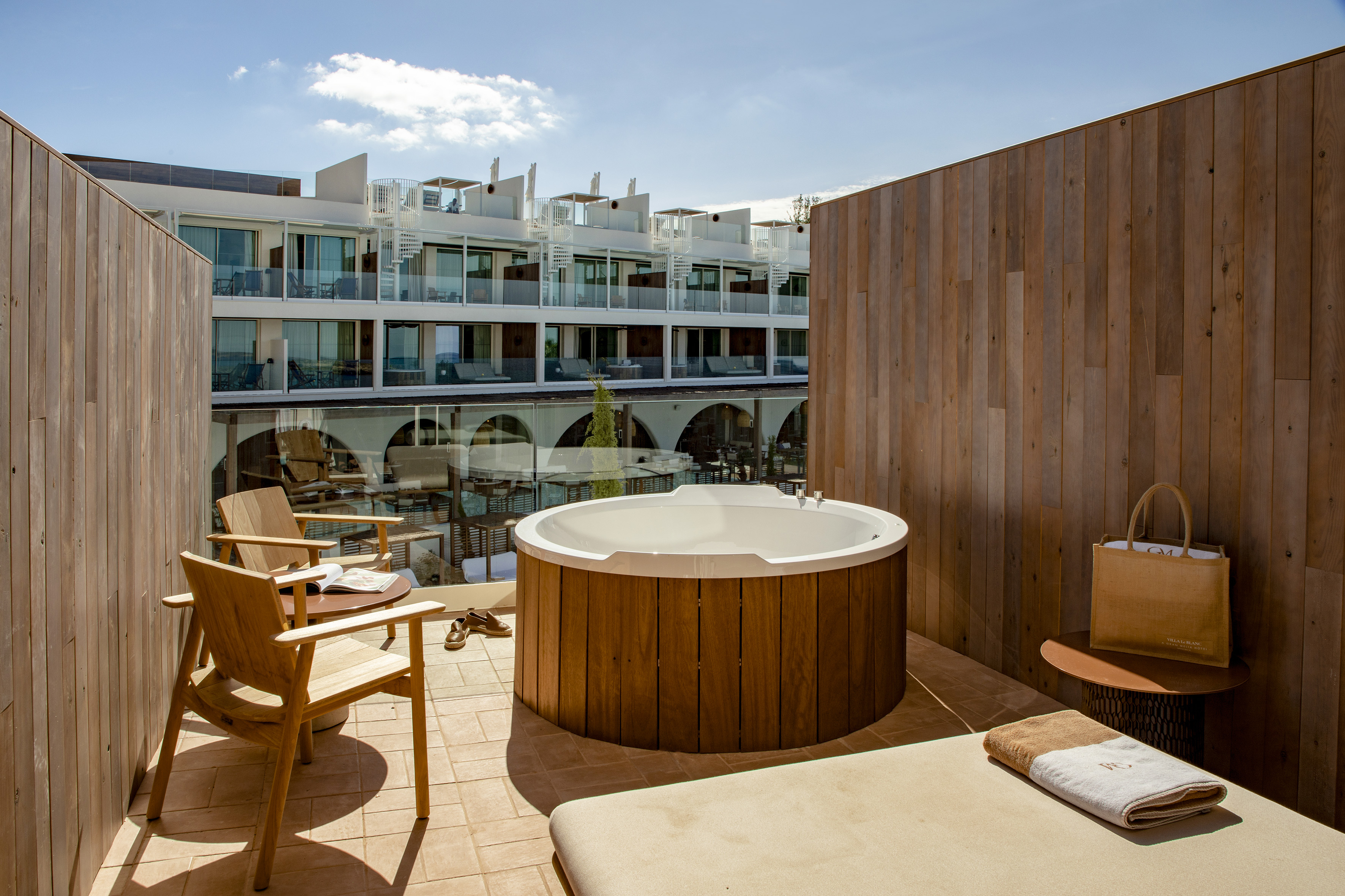 Luxury hotel balcony with private wooden hot tub and outdoor furniture.
