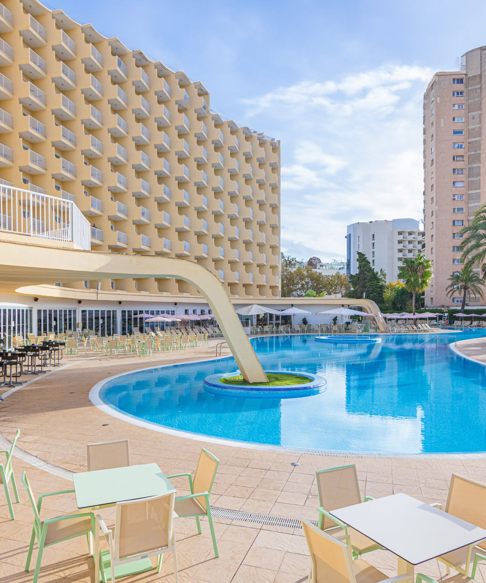 a pool with tables and chairs in front of a building