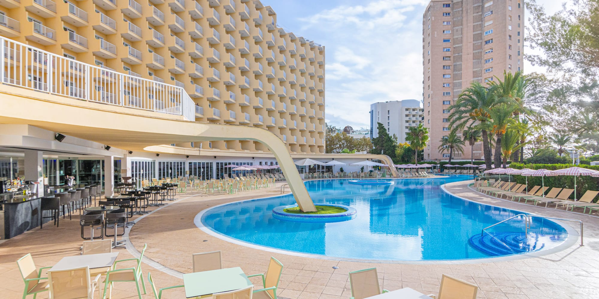 a pool with tables and chairs in front of a building