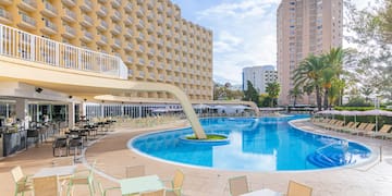 a pool with tables and chairs in front of a building