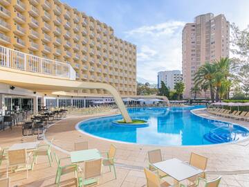 a pool with tables and chairs in front of a building