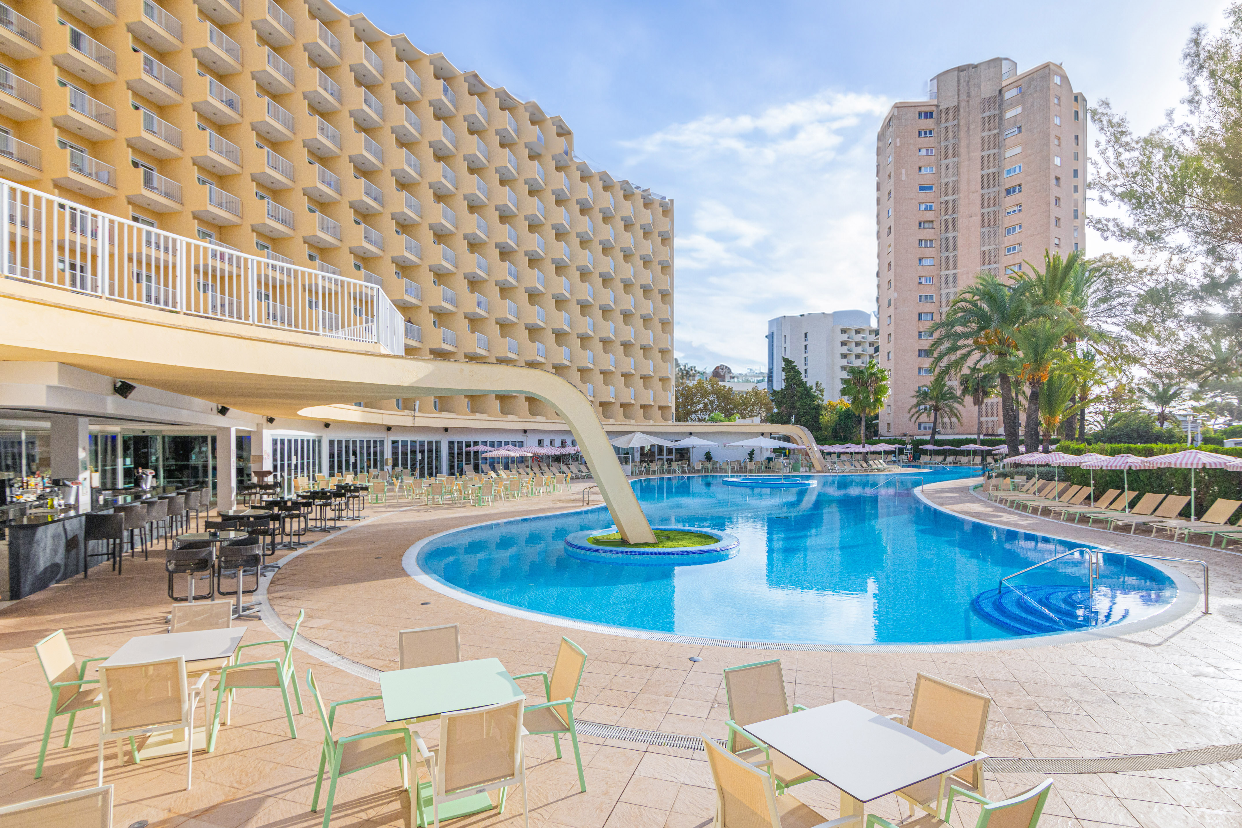 a pool with tables and chairs in front of a building