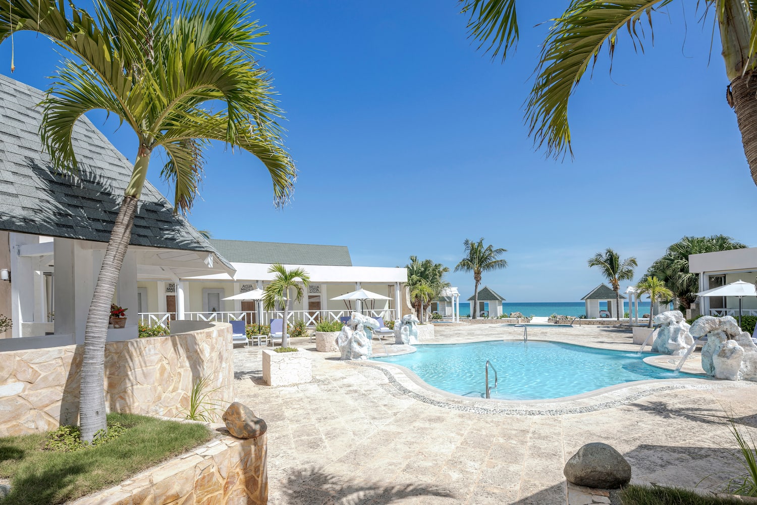 a swimming pool with a white building and palm trees
