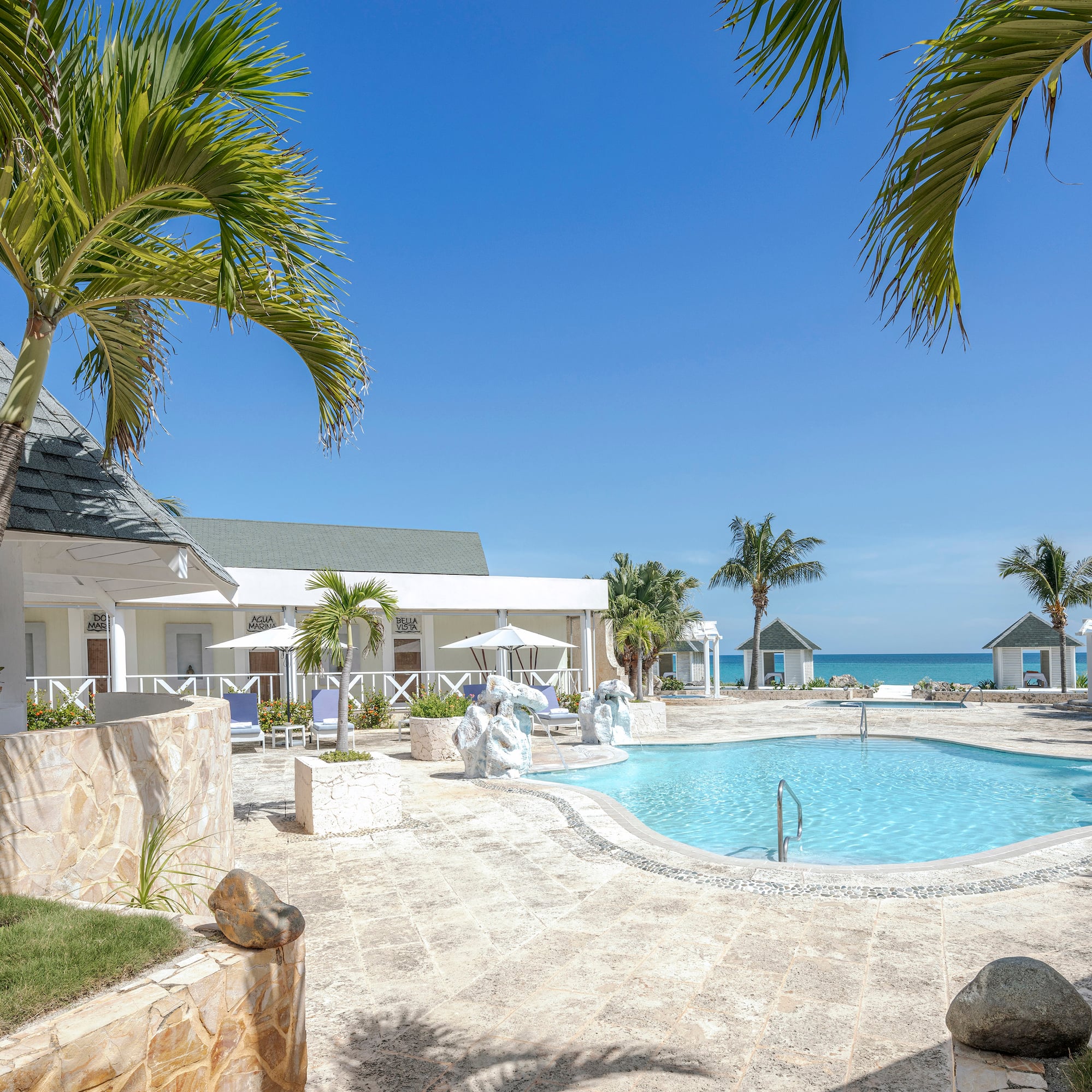 a swimming pool with a white building and palm trees