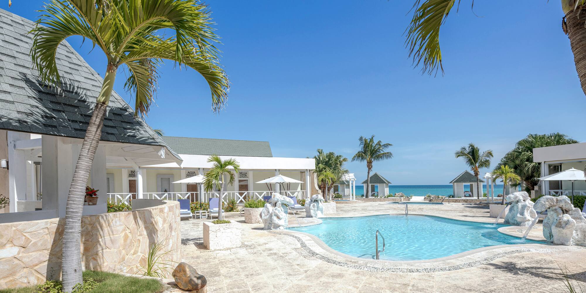 a swimming pool with a white building and palm trees