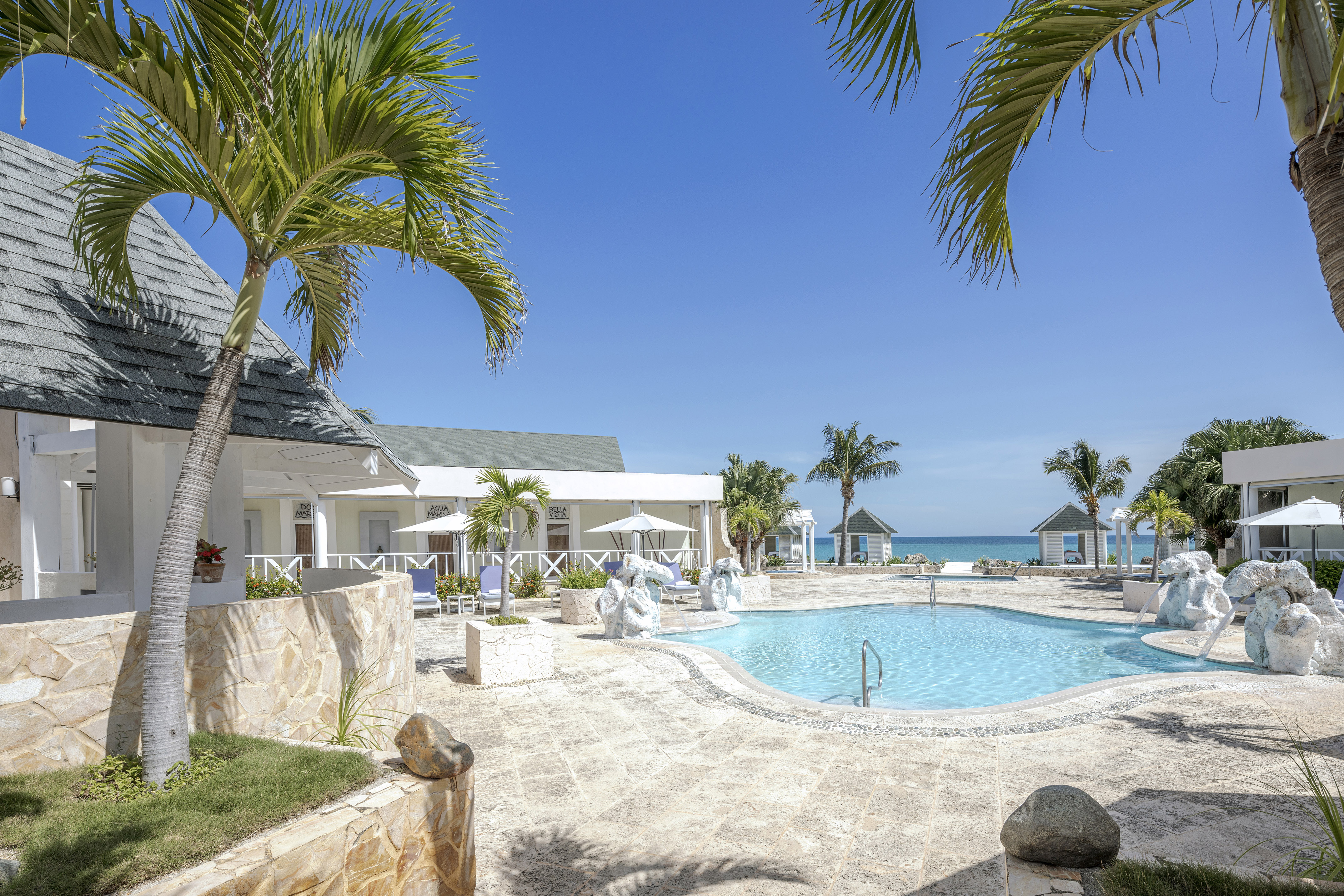 a swimming pool with a white building and palm trees