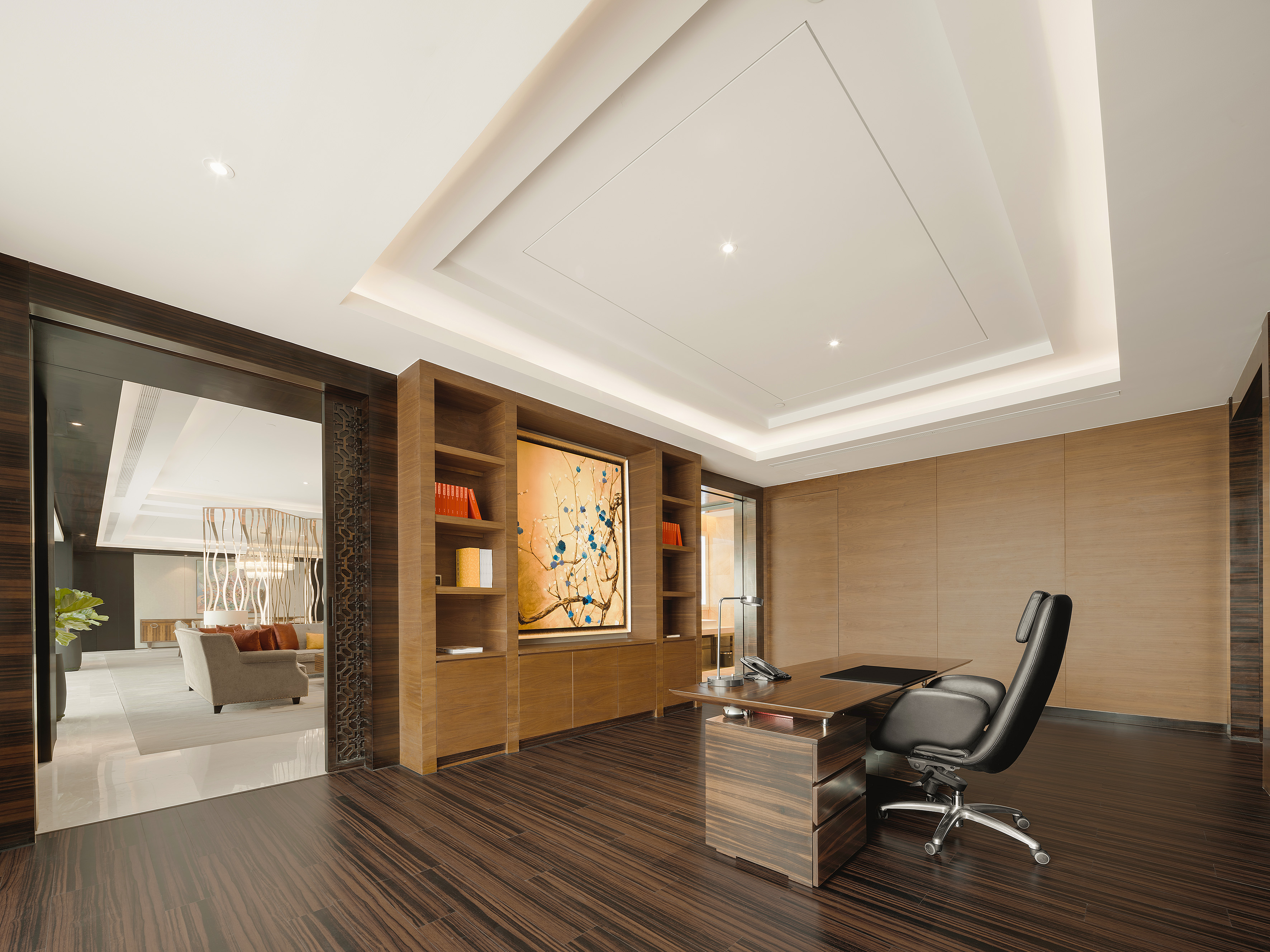 Modern executive office with dark wood flooring, desk, and built-in shelves.