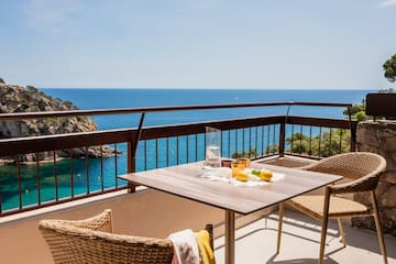 a table and chairs on a balcony overlooking the ocean