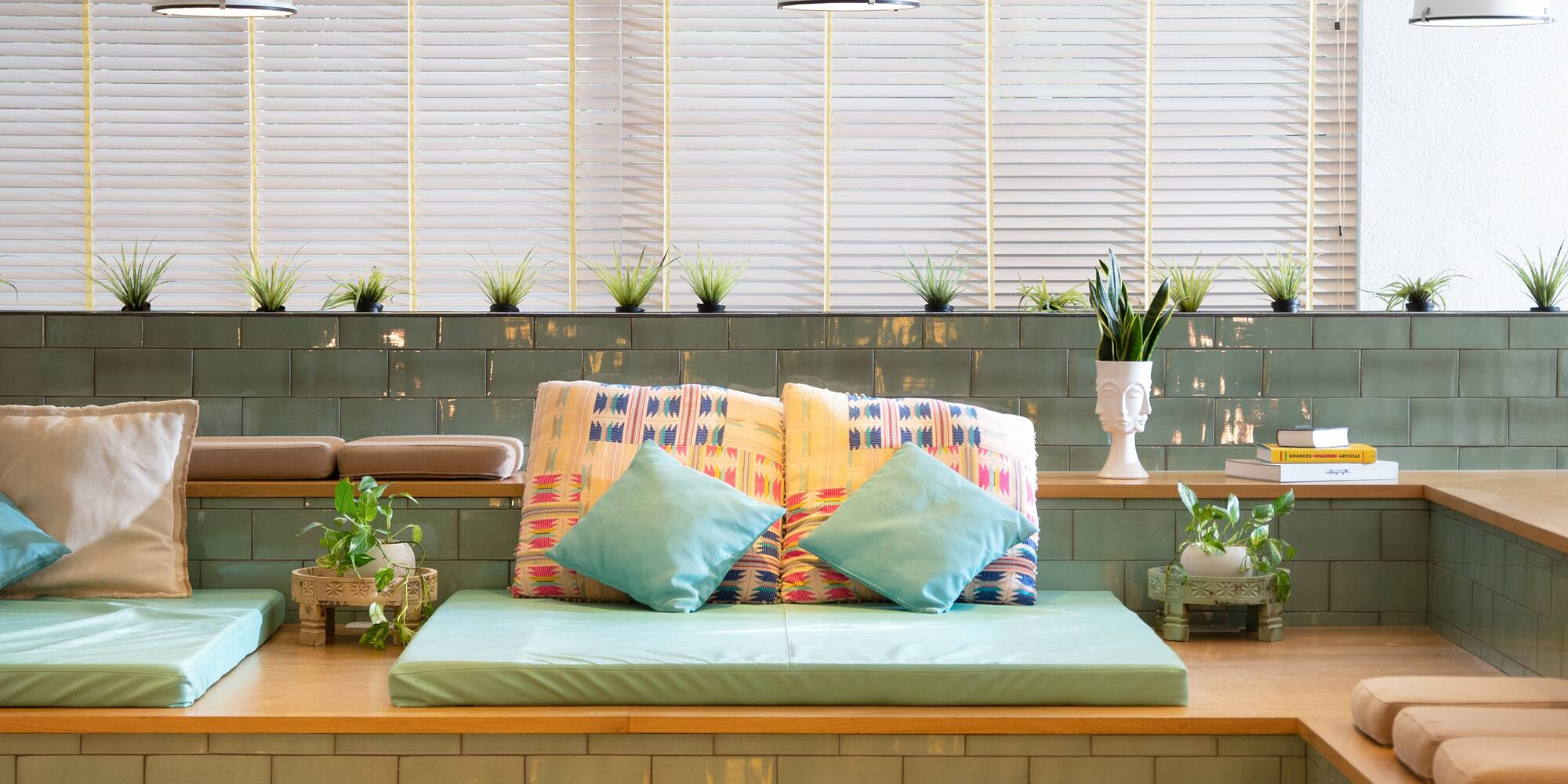 a couch with pillows and a bench in a room with plants