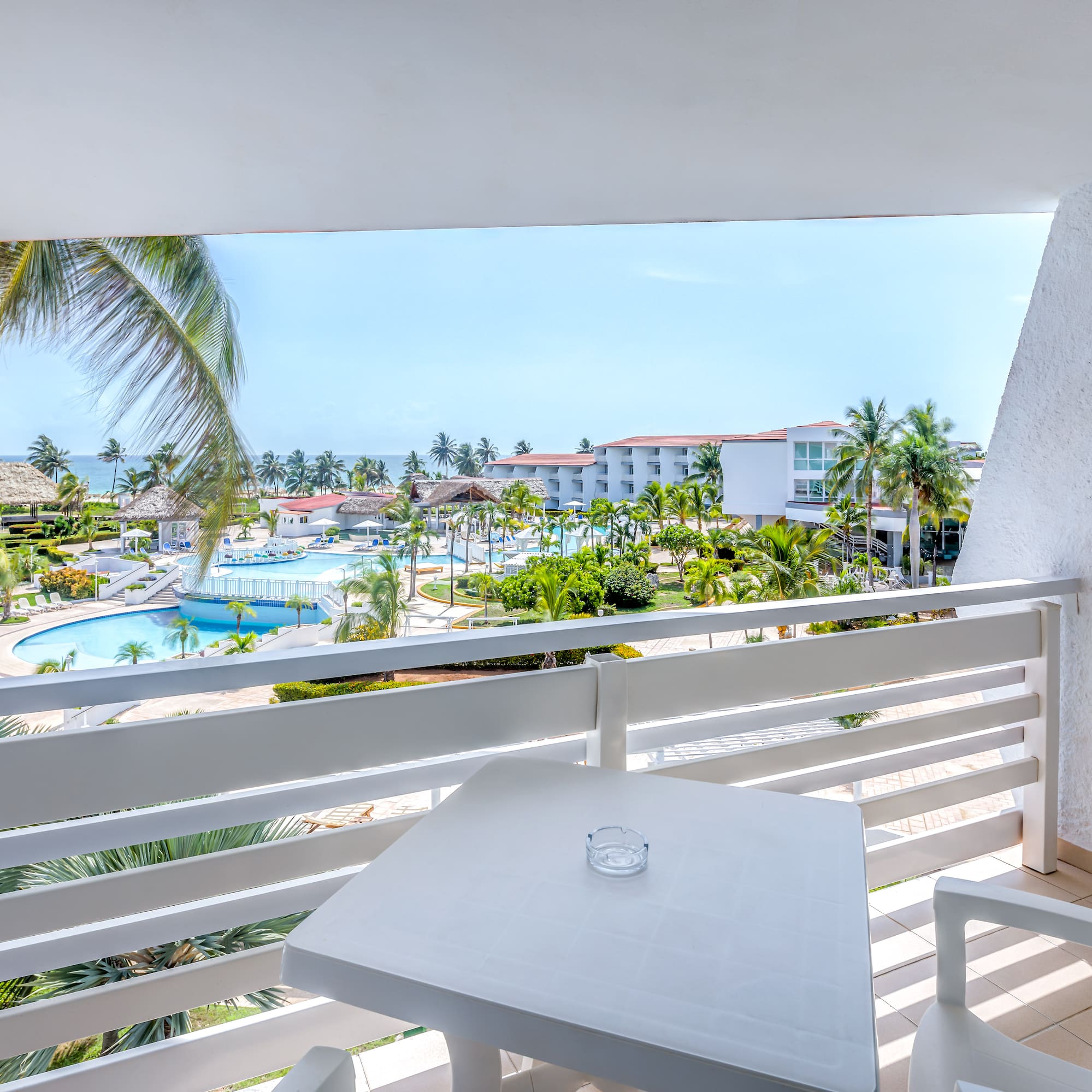 a table and chairs on a balcony overlooking a pool and buildings