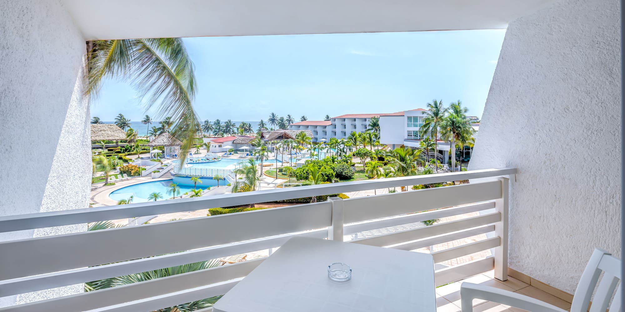 a table and chairs on a balcony overlooking a pool and buildings
