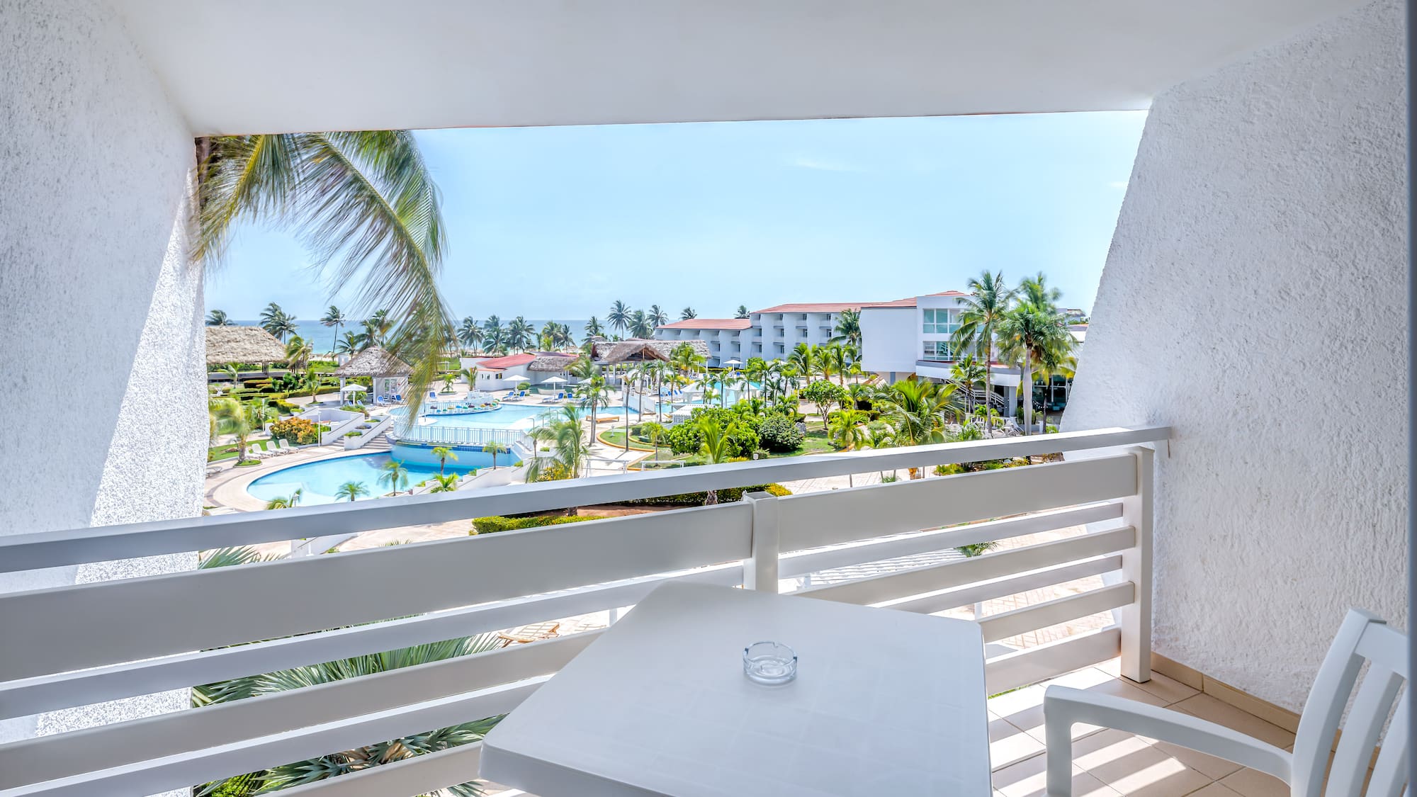 a table and chairs on a balcony overlooking a pool and buildings