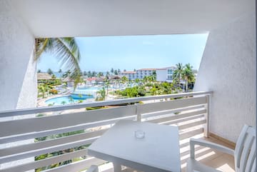 a table and chairs on a balcony overlooking a pool and buildings