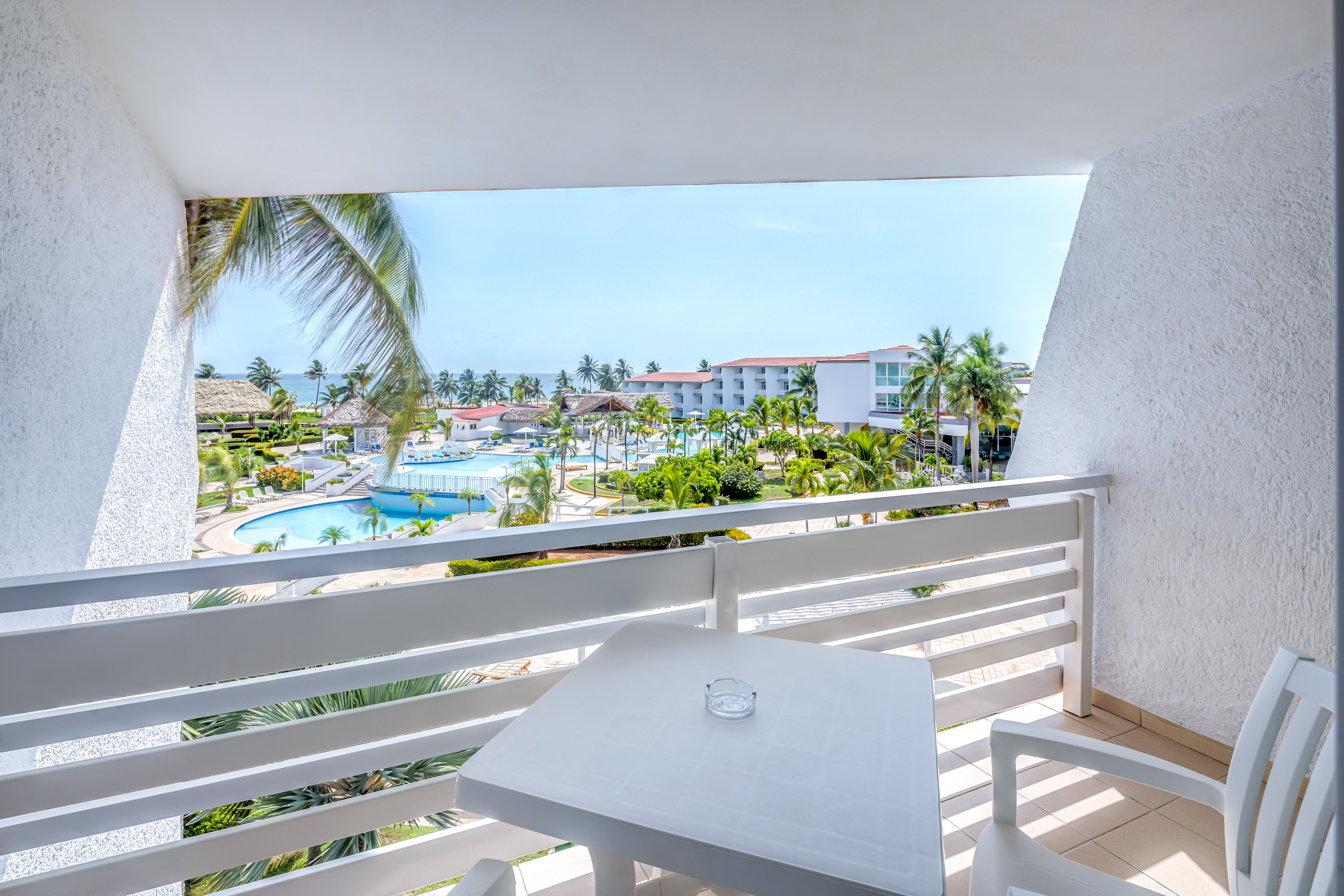 a table and chairs on a balcony overlooking a pool and buildings