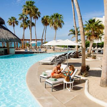 a man and woman sitting on a lounge chair next to a pool