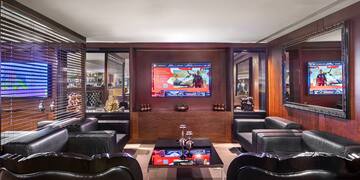 a room with black leather chairs and a tv on the wall