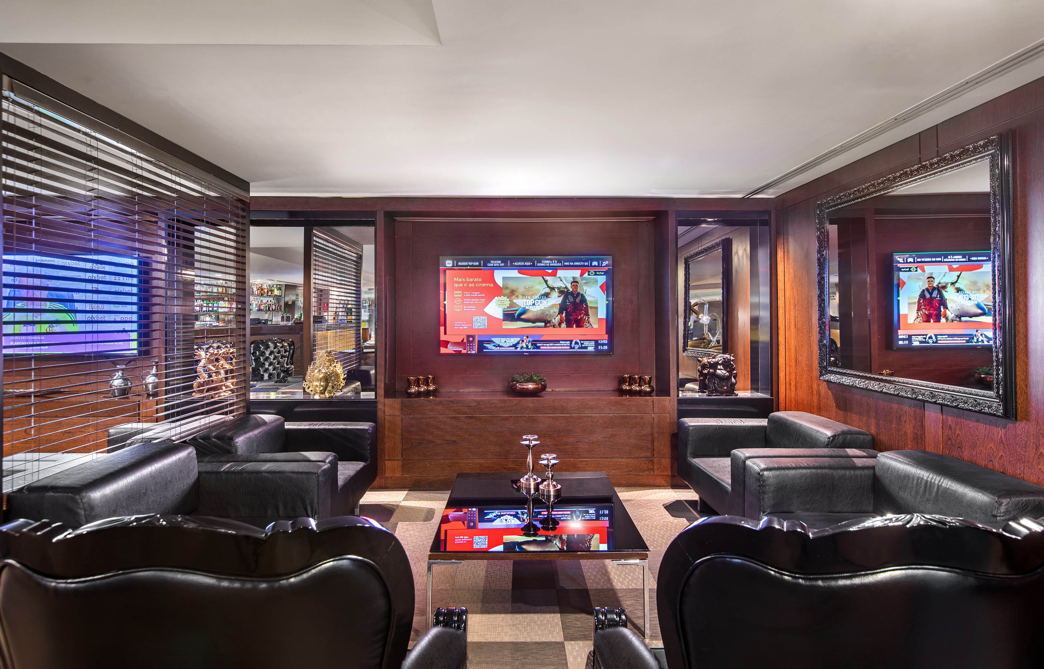 Modern luxury lounge with black leather seating, large TV, dark wood walls.