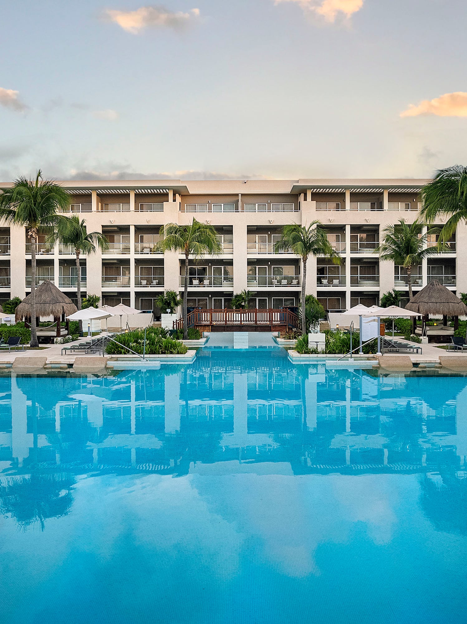 a swimming pool with palm trees and a building