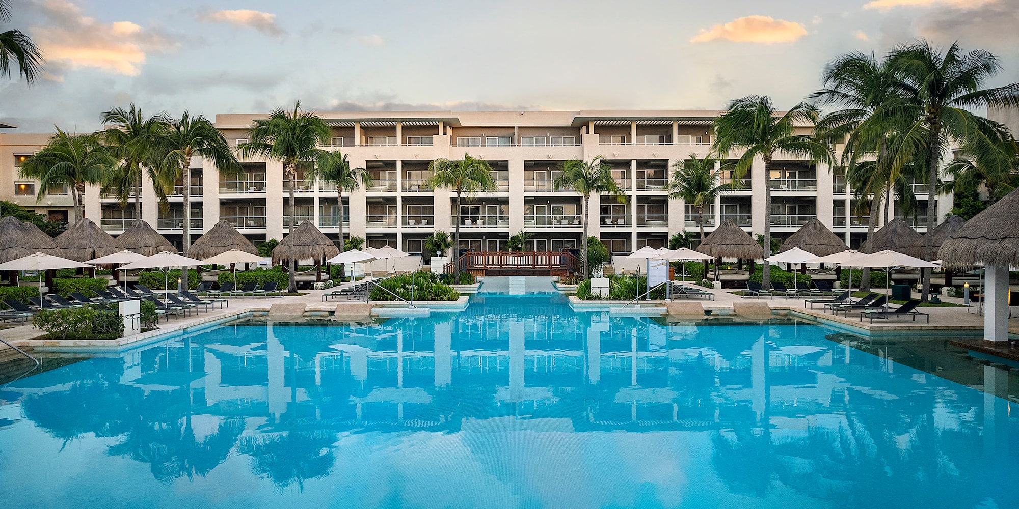 a swimming pool with palm trees and a building