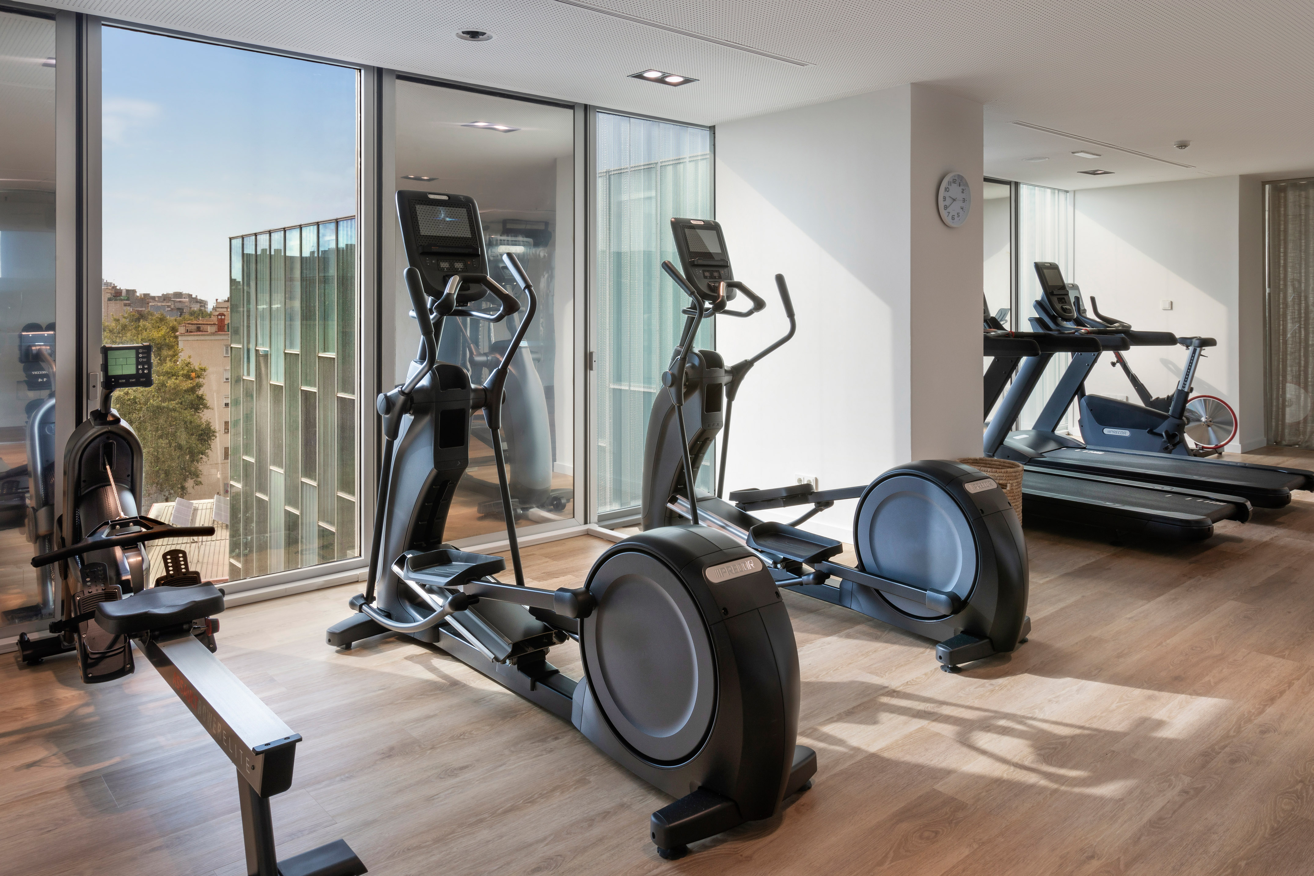 Fitness room with ellipticals, treadmill, rowing machine, city views.