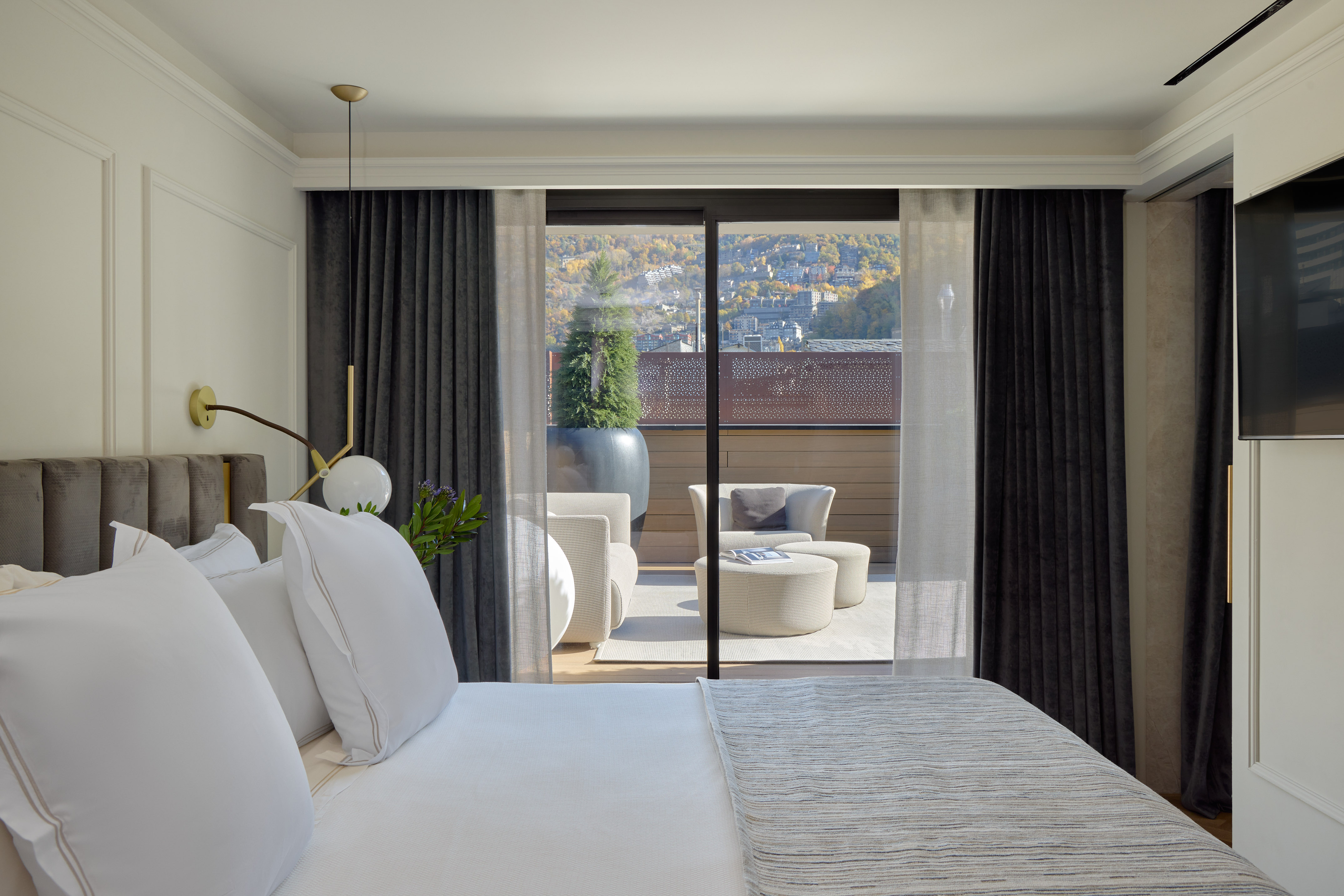 Luxury hotel suite bedroom with balcony terrace and scenic mountain view.