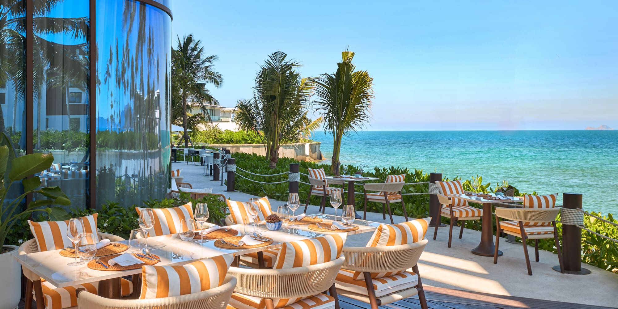 a restaurant with tables and chairs on a deck overlooking the ocean