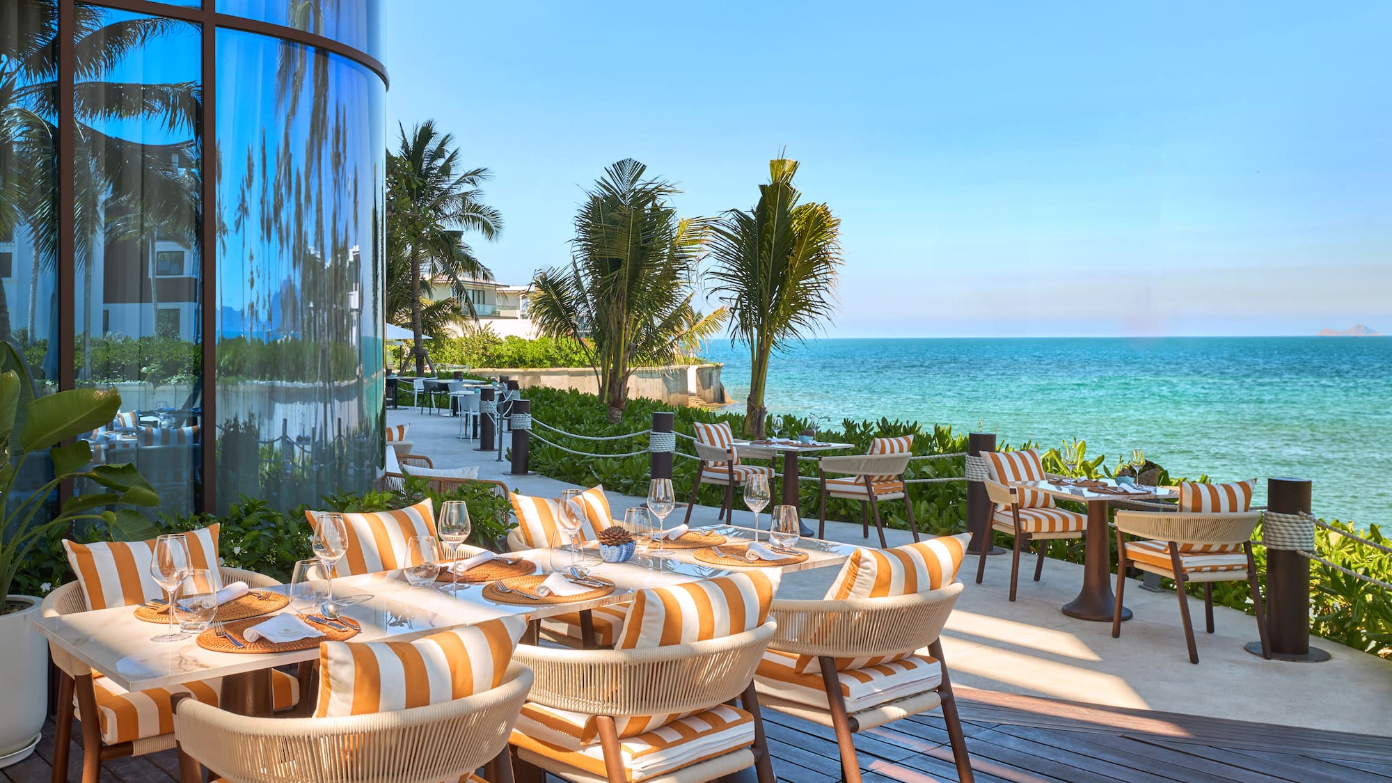 a restaurant with tables and chairs on a deck overlooking the ocean
